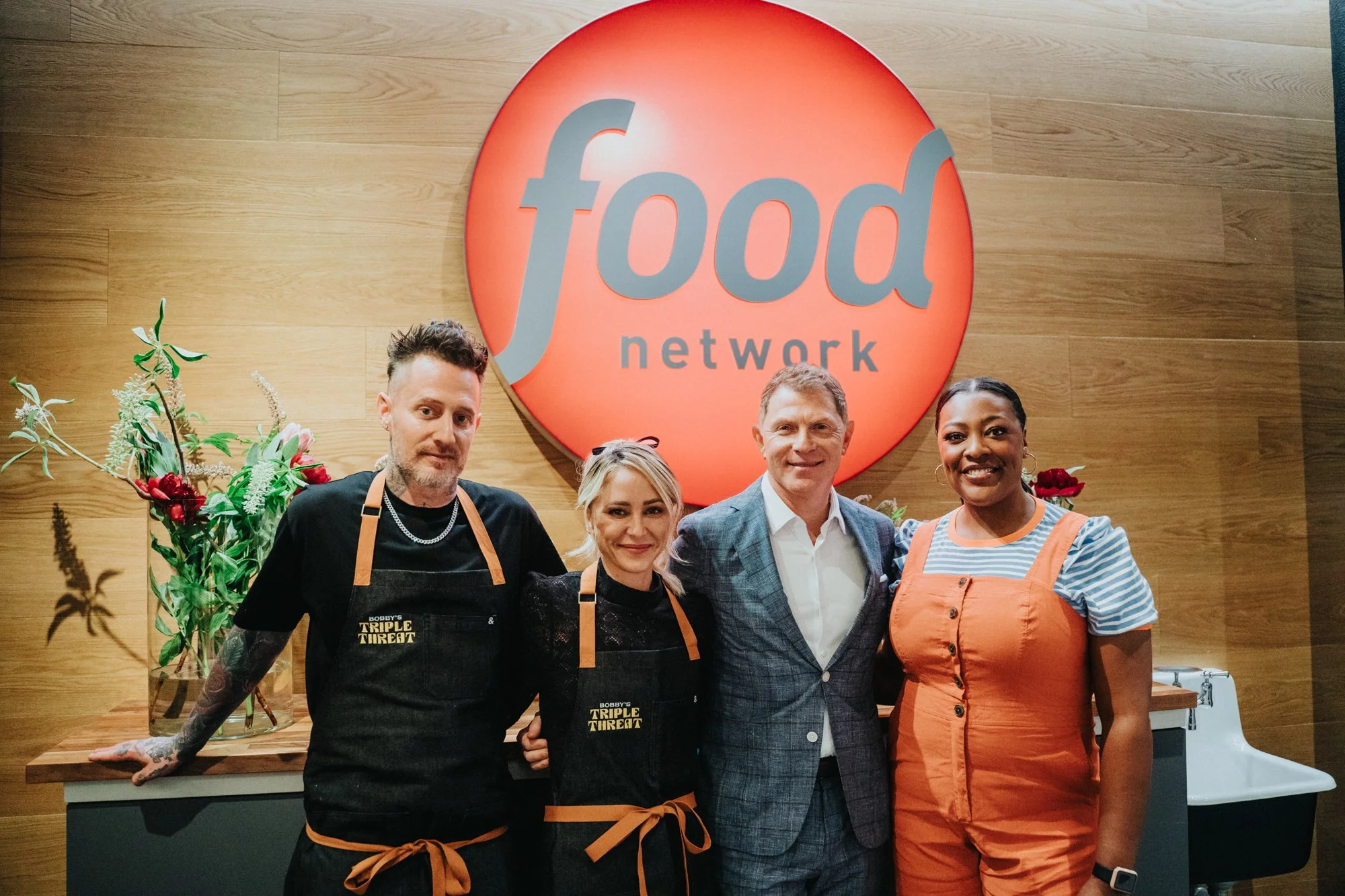  Bobby Flay and chefs in front of the Food Network logo 
