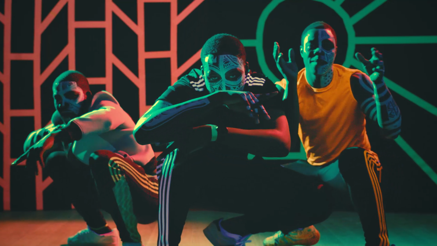 Three men in face paint squatting