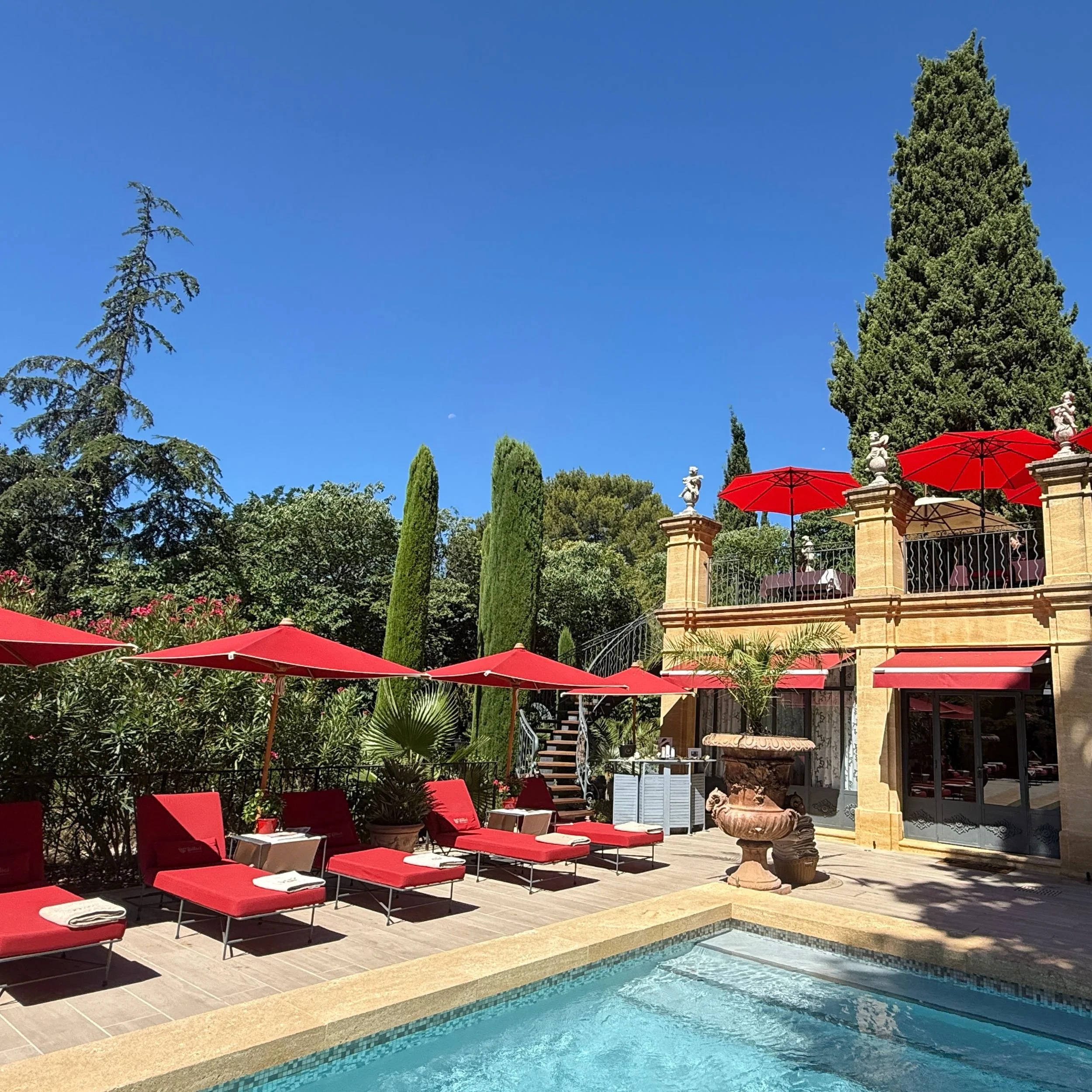 Pool area at Villa Gallici with red parasols overlooking the spa and Dolce Serata terrace