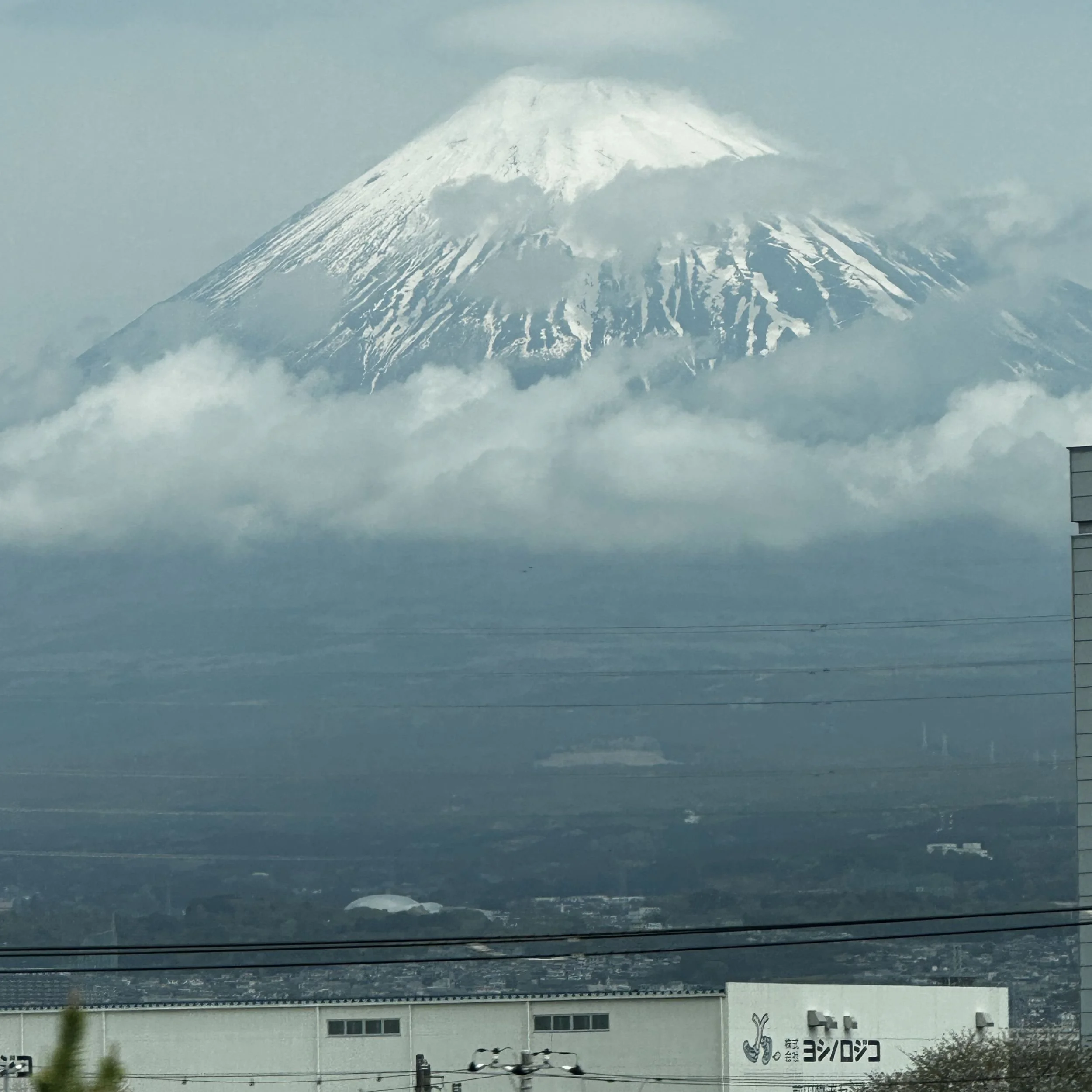 Mount Fuji seen from the Shinkansen with cloud wrapped around the summit and lower slopes.
