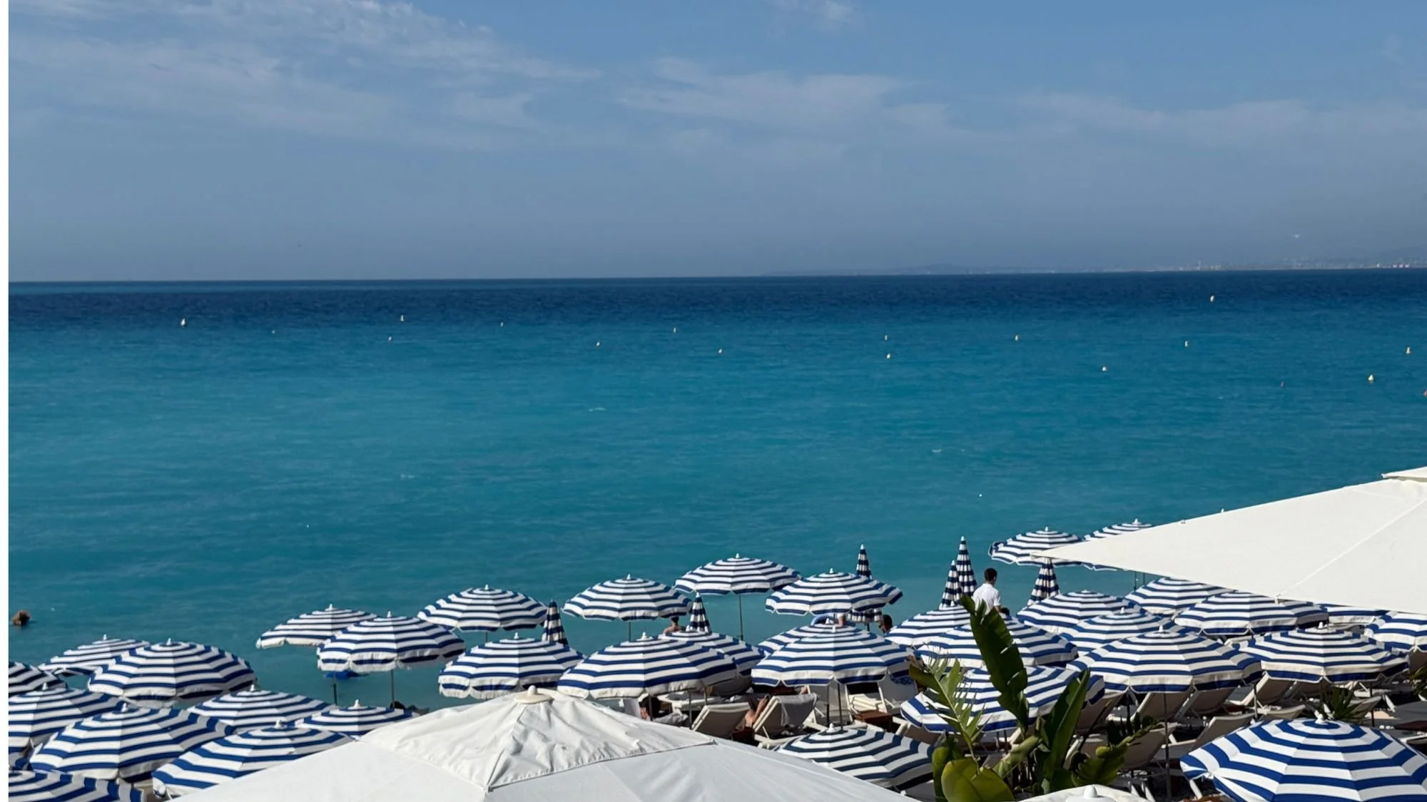  Row of classic blue and white striped beach umbrellas at an exclusive private beach club along the Promenade des Anglais in Nice France. 