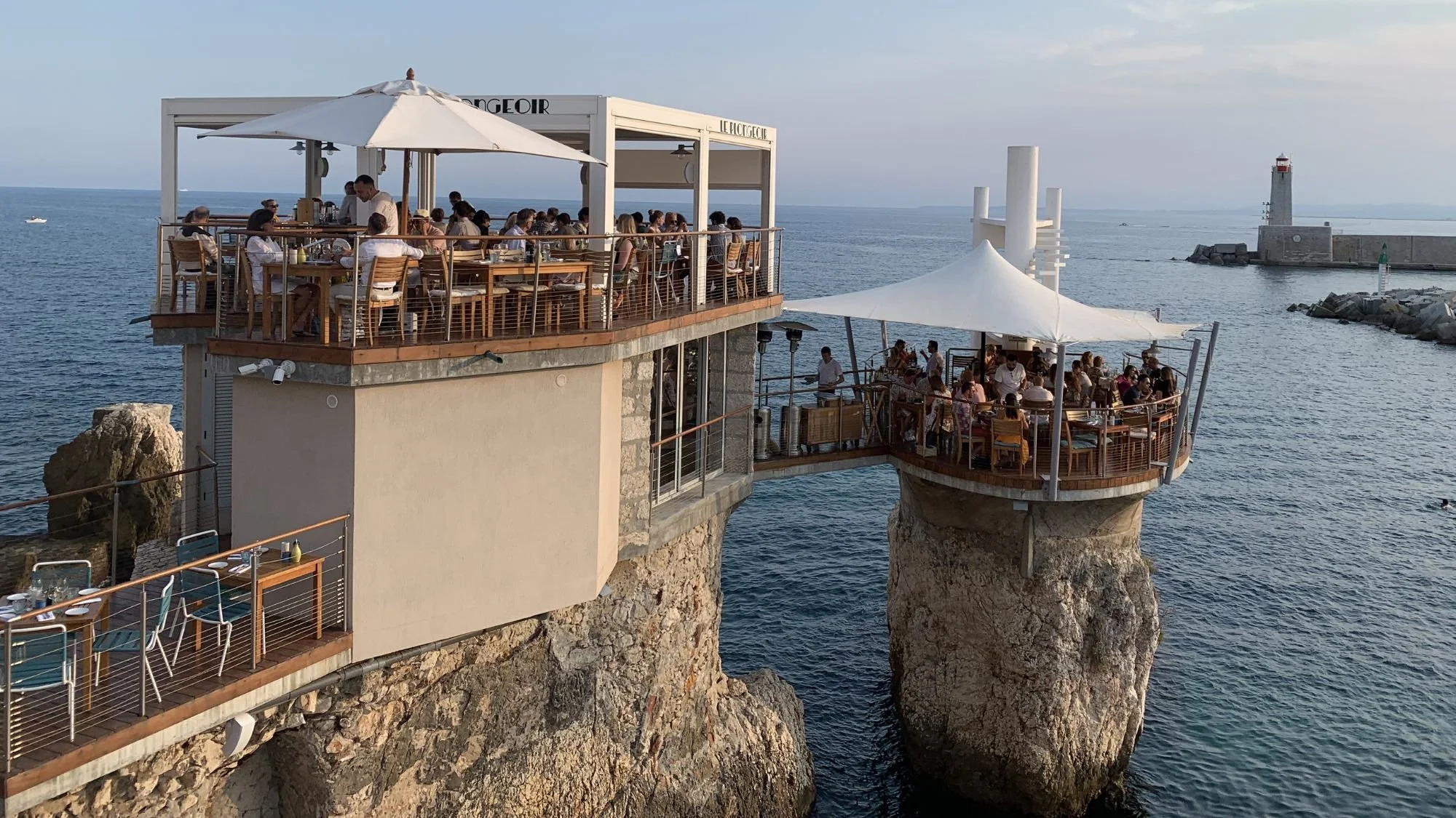  Diners enjoying an outdoor meal at Le Plongeoir restaurant perched on an iconic sea diving platform in Nice France. 