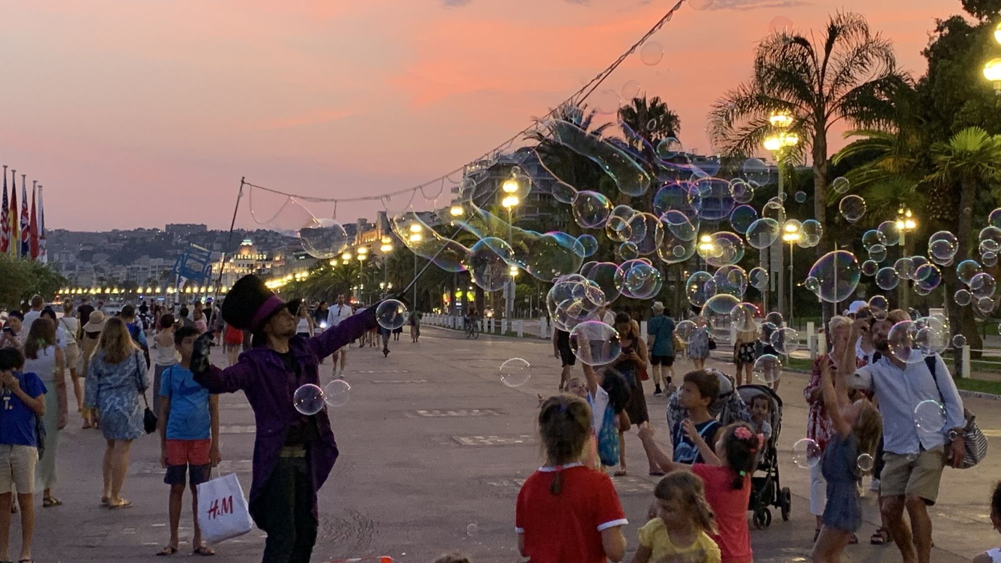  A street performer making large bubbles for children on the Promenade des Anglais at sunset in Nice France. 