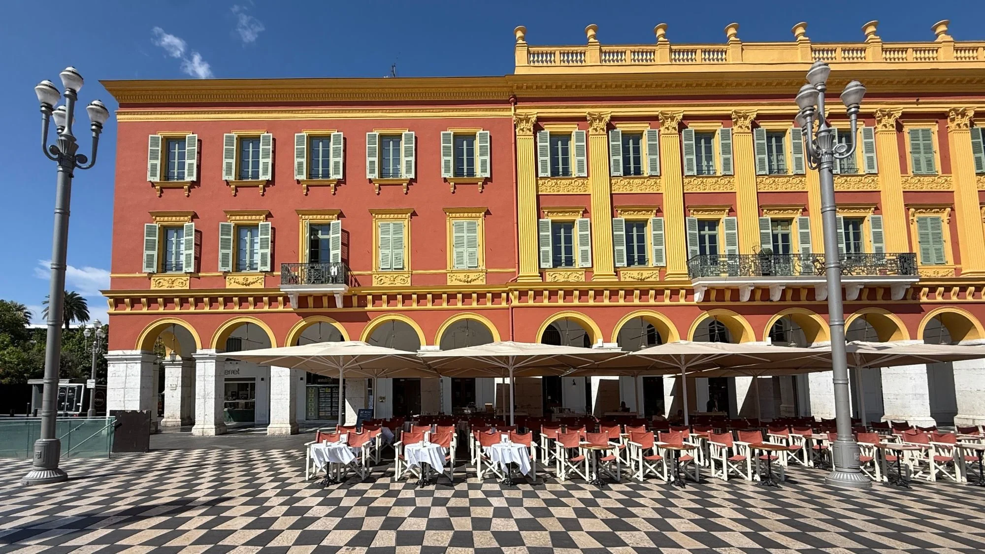  The striking checkerboard pavement and elegant terracotta arcade buildings of Place Masséna in Nice France. 