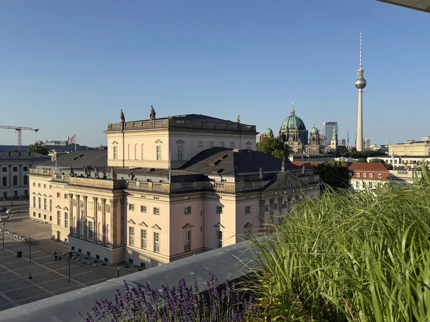 The view from Hotel de Rome rooftop bar across to the Berlin state opera and further to the domes of Musuem Island and the TV tower against a blue sky