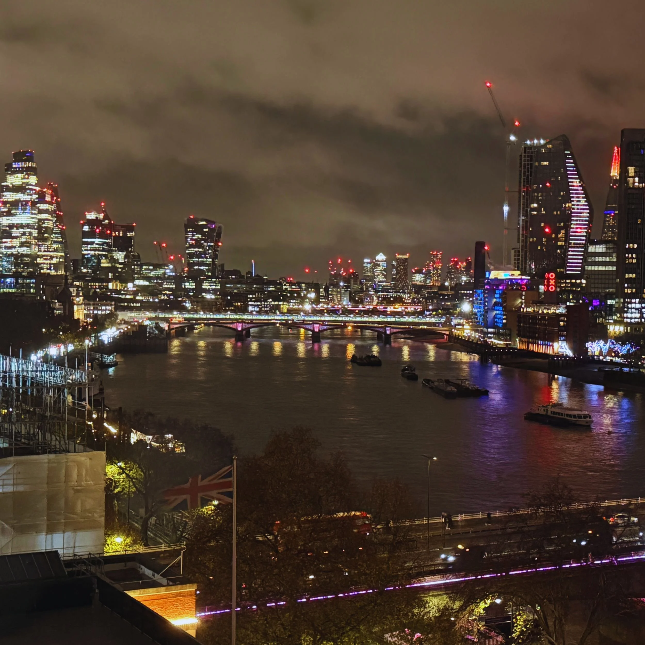 A cloudy dark sky looms over the city of London looking down the Thames towards Canary Wharf