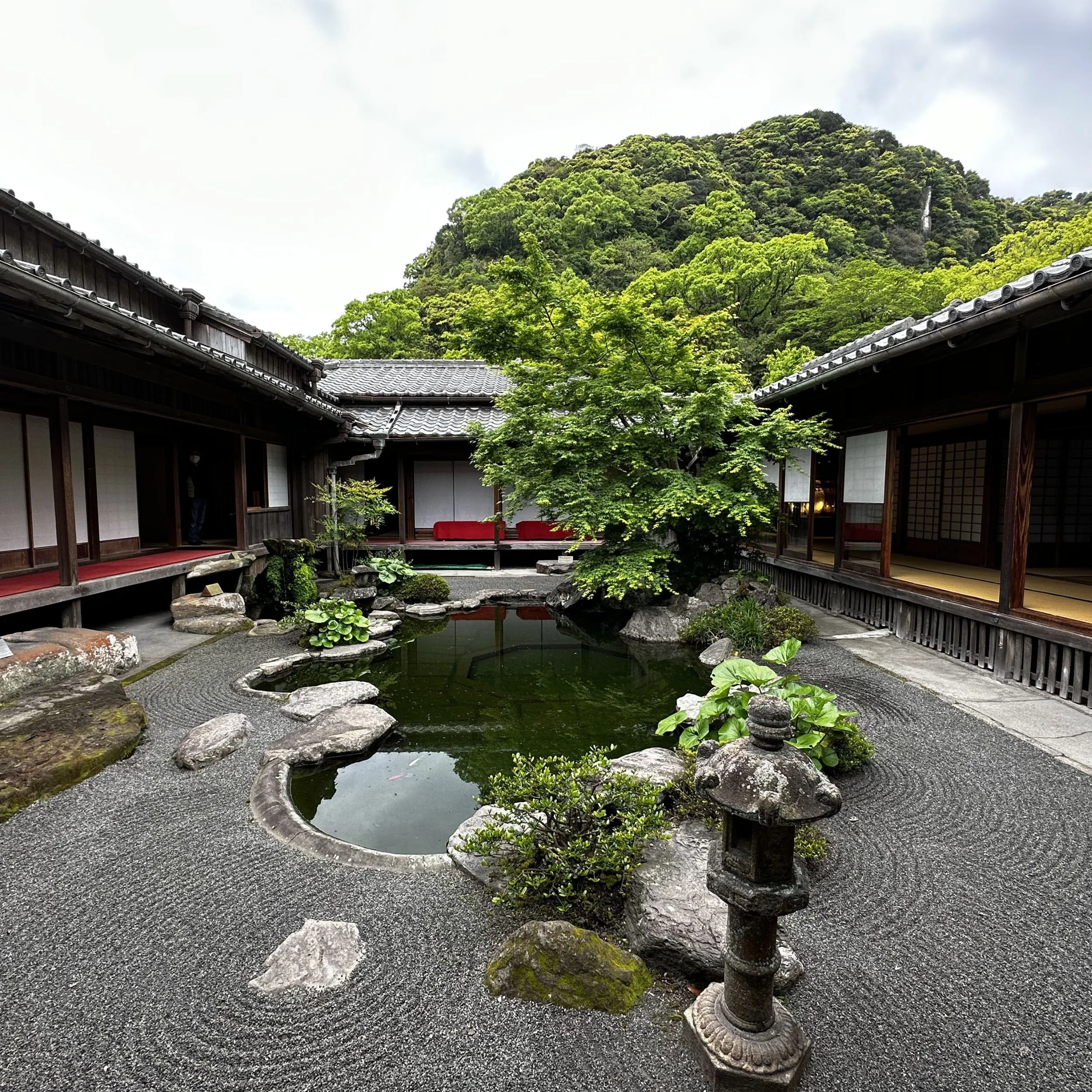 Traditional courtyard garden inside the Sengan-en estate in Kagoshima with raked gravel, pond, stone lantern and wooden buildings