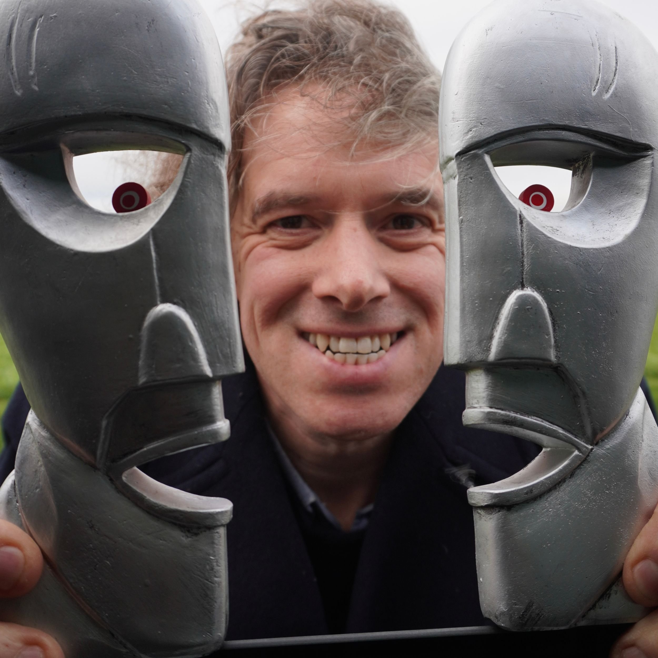 Jamie Riddell framed between two Division Bell head sculptures, echoing the Pink Floyd album cover symbolism