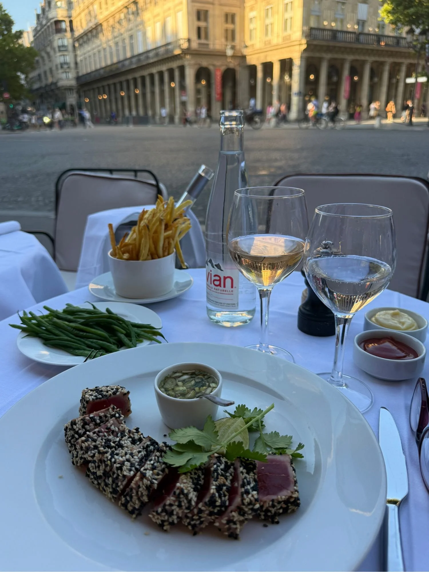 Seared sesame-crusted tuna served with matchstick frites, green beans, and chilled rosé on the terrace at Café Ruc in Paris.