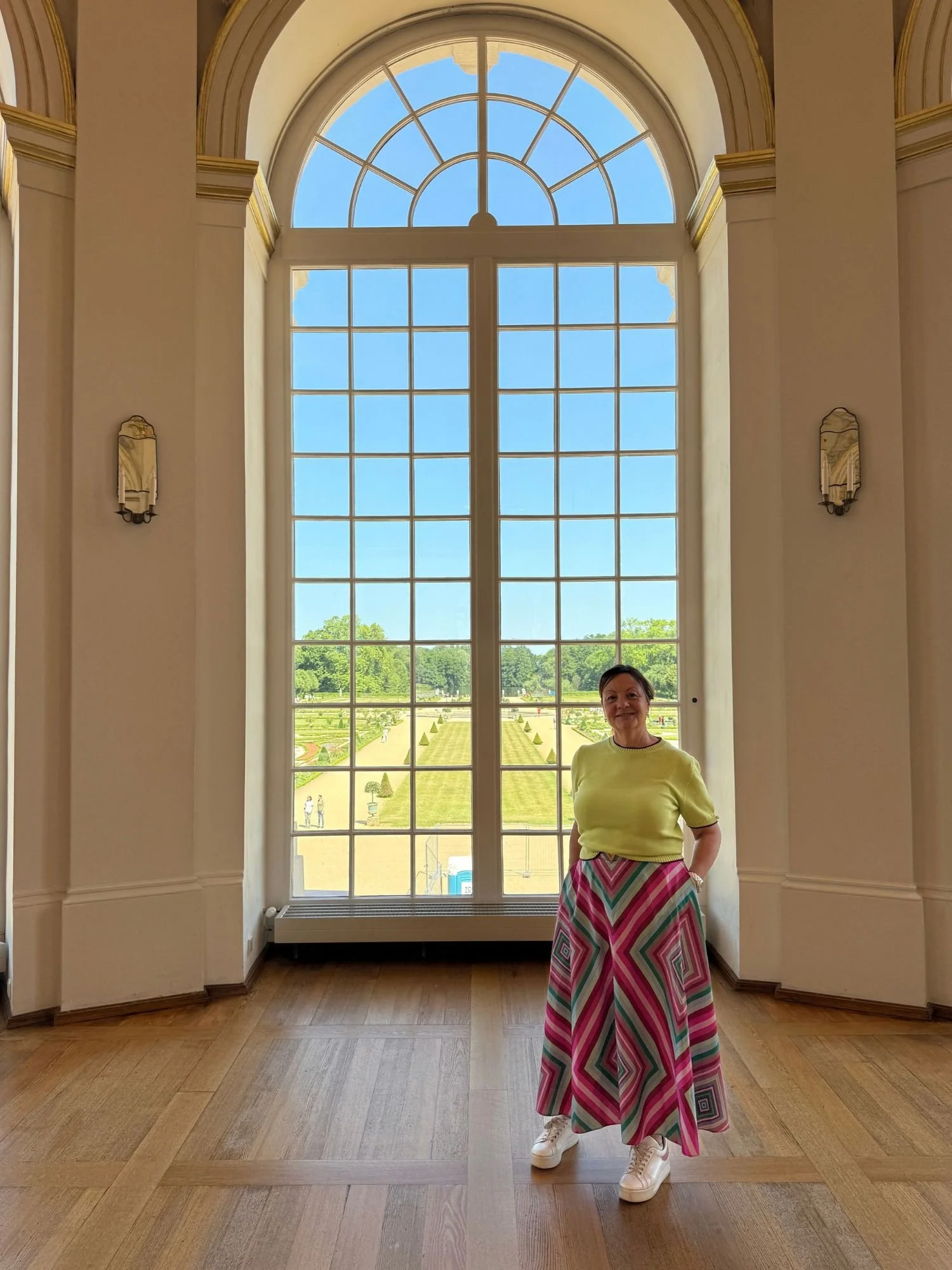 Tall arched multi-paned window overlooking the formal Baroque gardens from the garden hall in Charlottenburg Palace