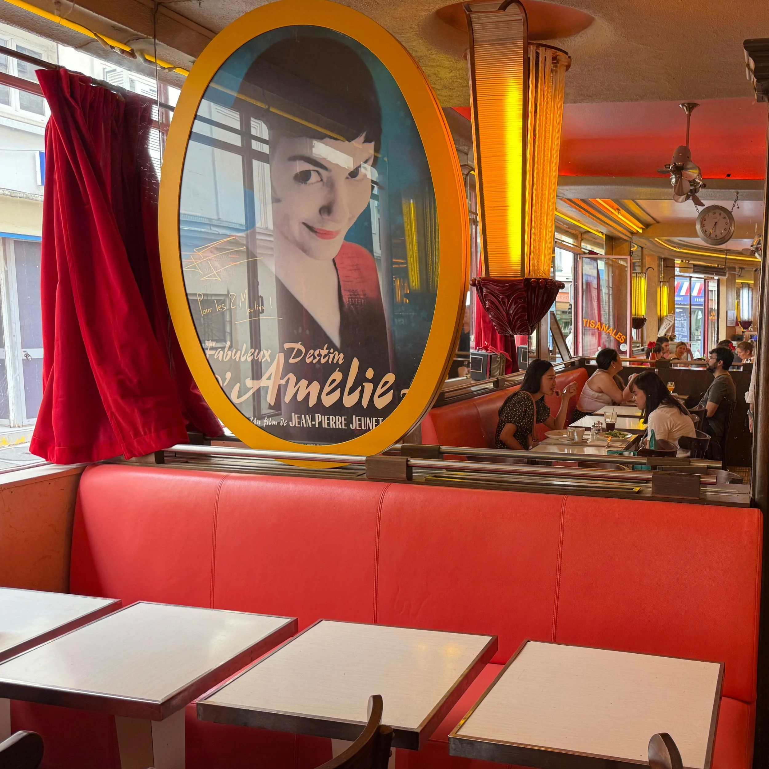 Inside the Amelie Cafe with red banquettes and a large picture of Amelie on the wall