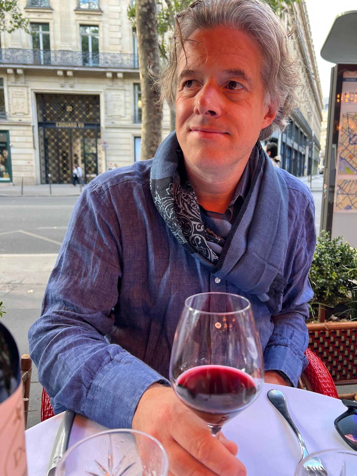 Jamie enjoying a glass of red wine outside on the terrace at Les Capucines restaurant in Paris