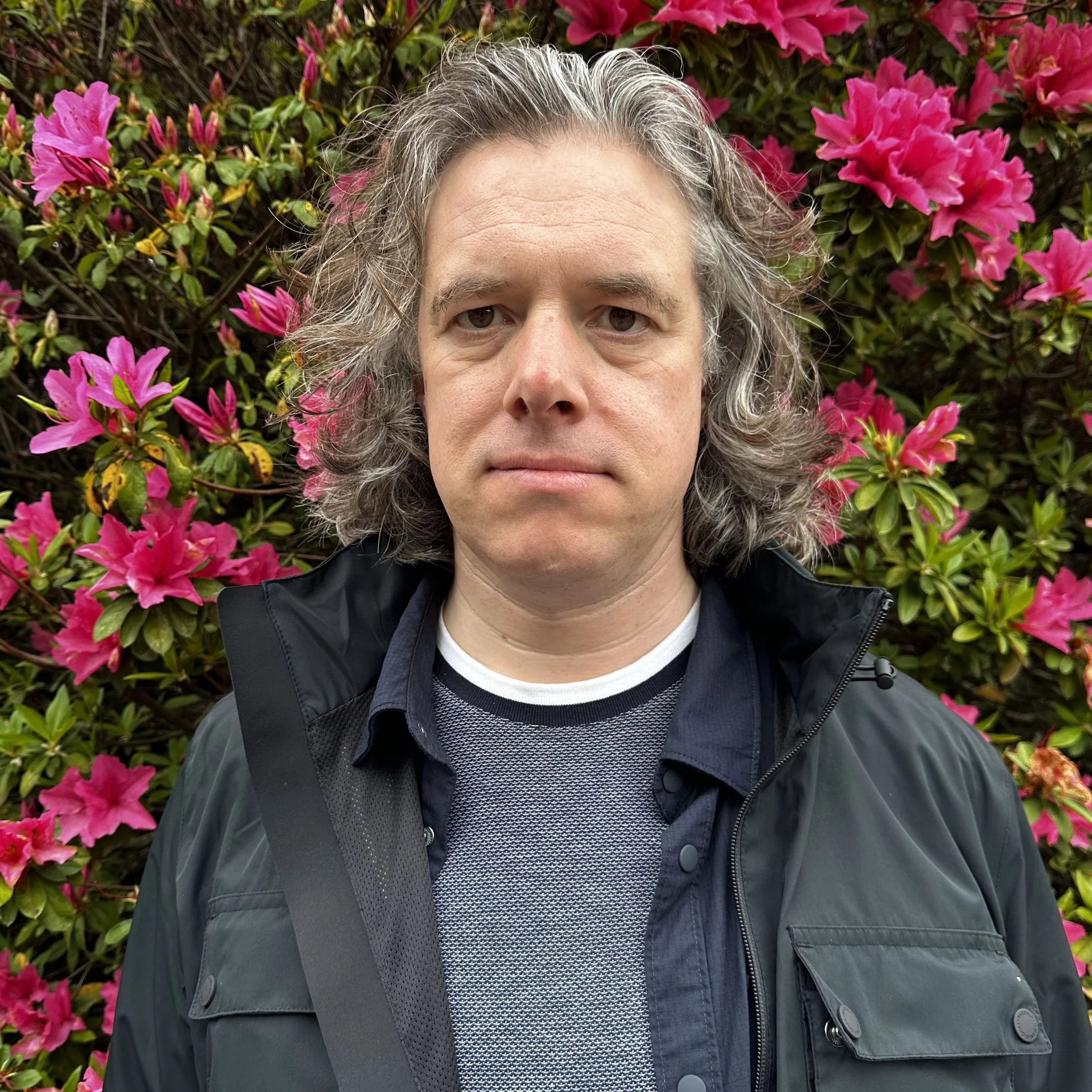 Jamie Riddell stands in front of colourful flowers in the Nagasaki Peace Park