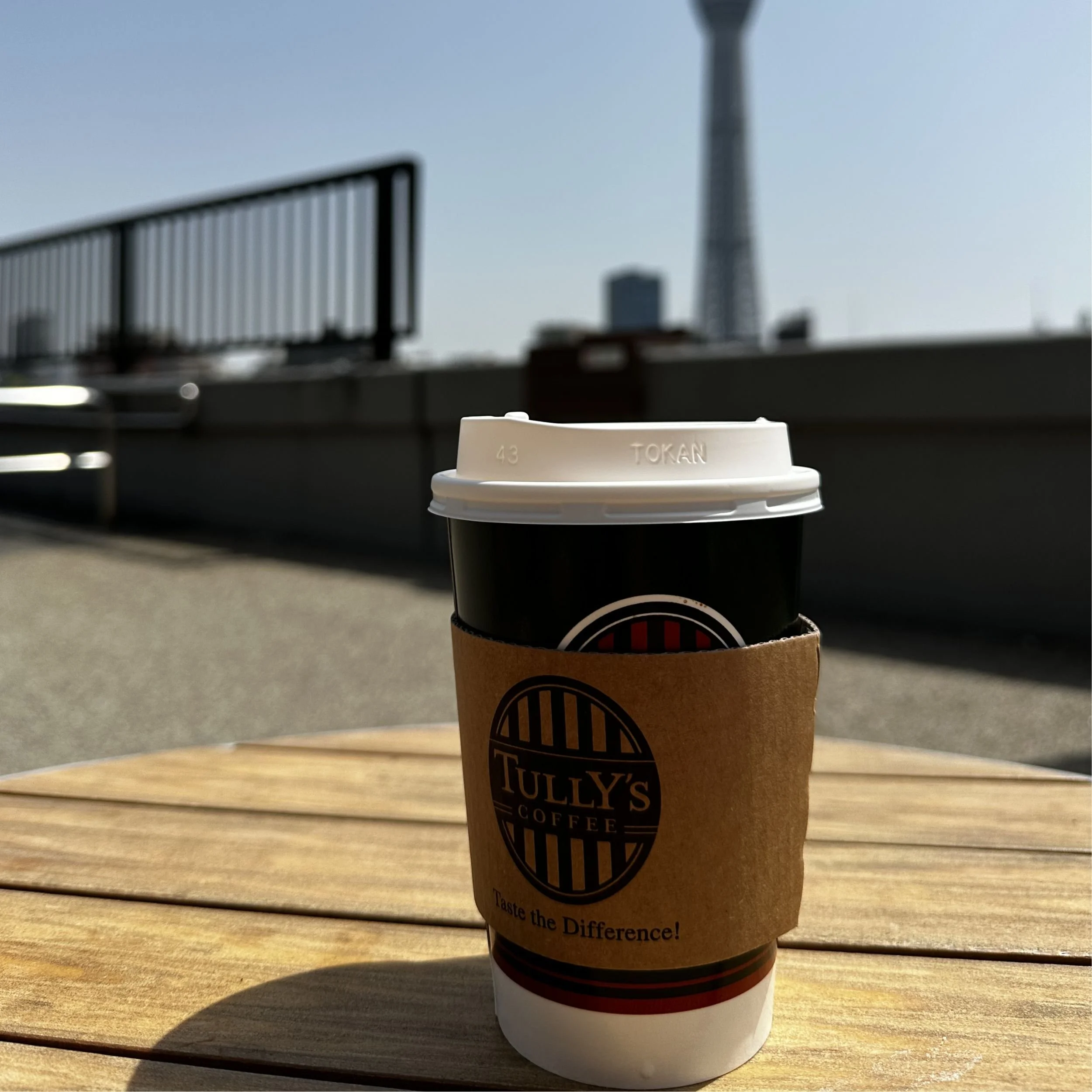 Tully’s Coffee cup on an outdoor table with Tokyo Skytree rising in the background in Tokyo