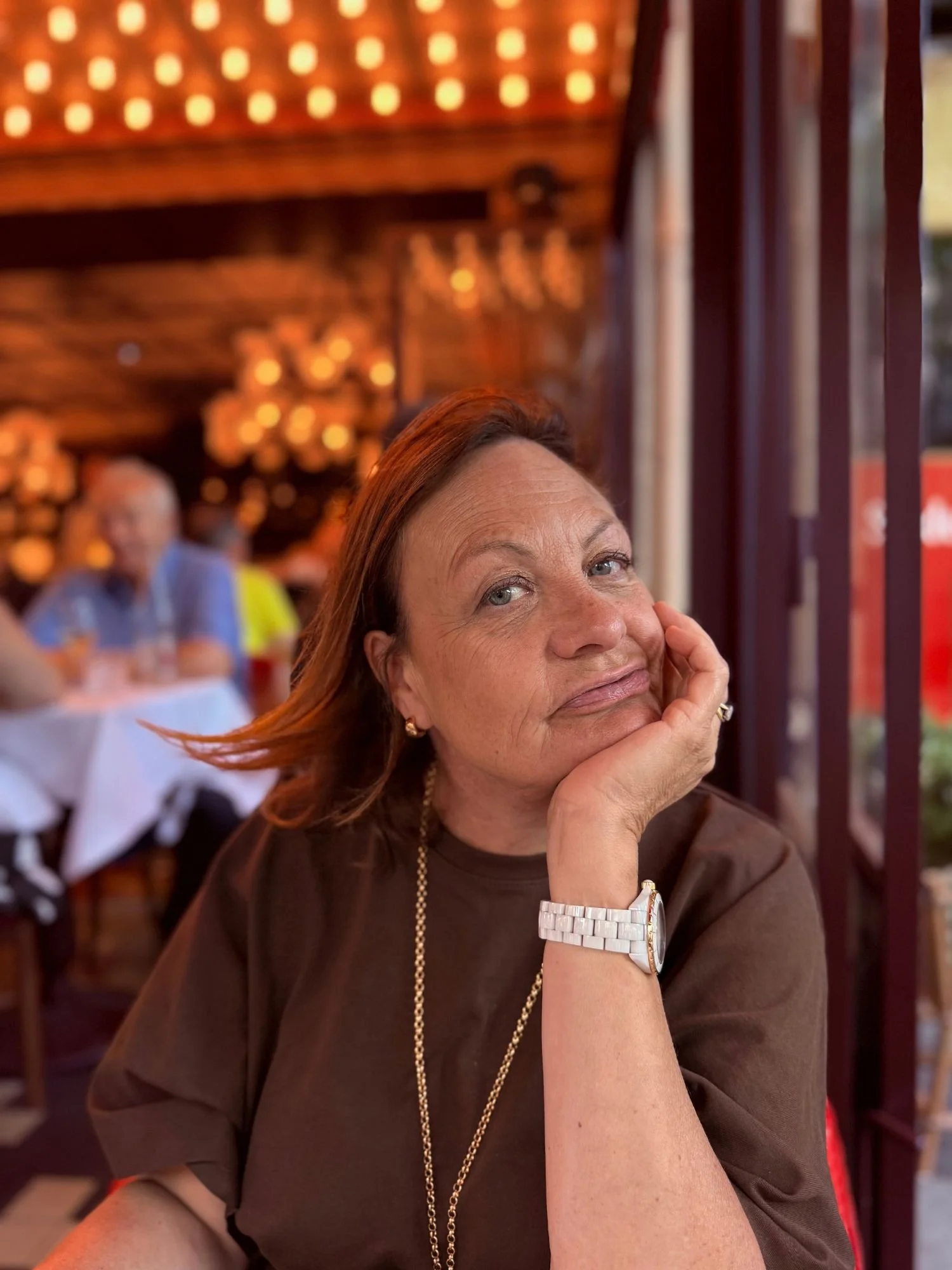 Katherine seated at an outdoor table beneath the awning at Les Capucines restaurant in Paris