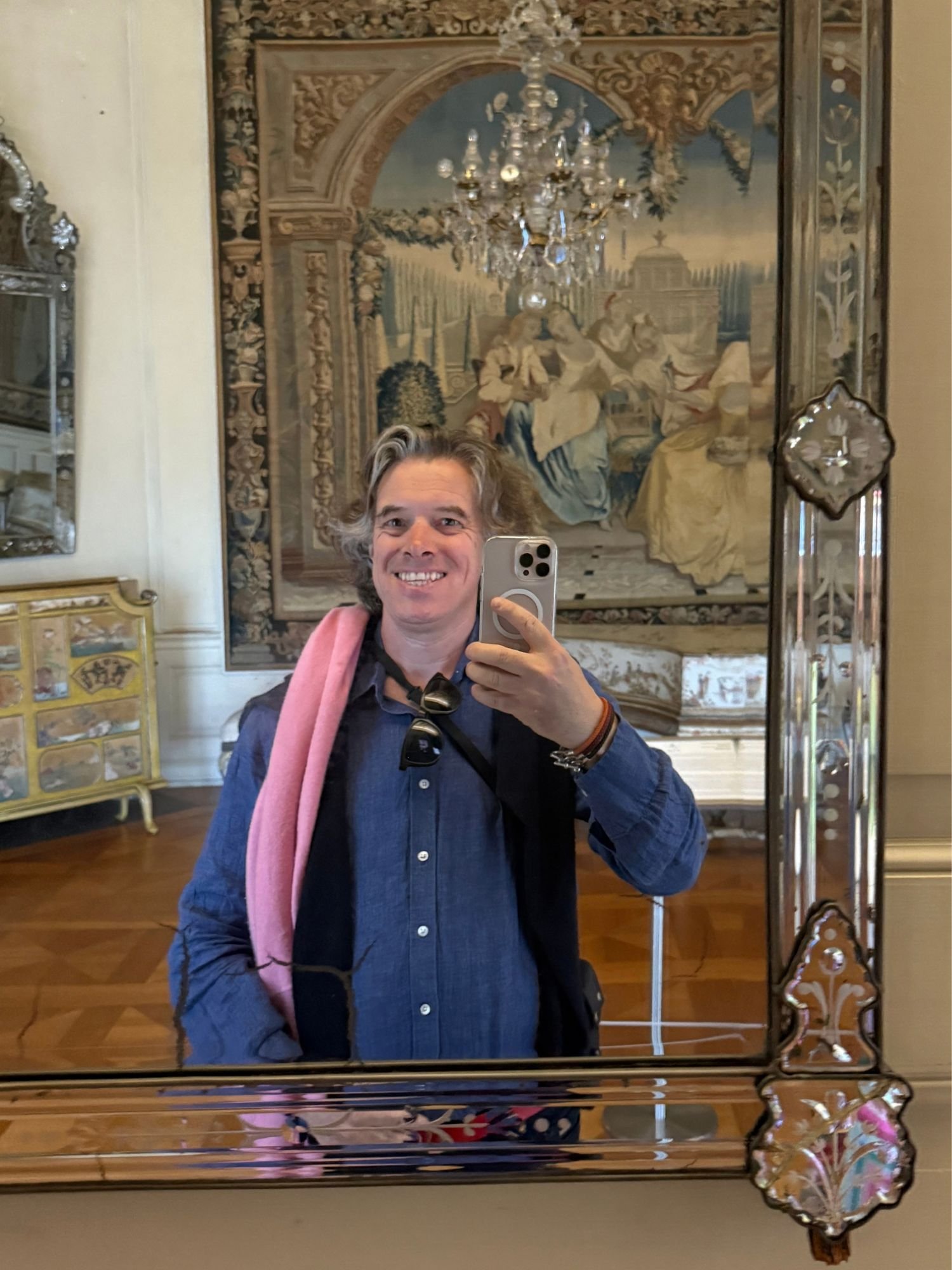 Mirror reflection of Jay inside Charlottenburg Palace, framed by an etched glass mirror with tapestries and chandelier in the background