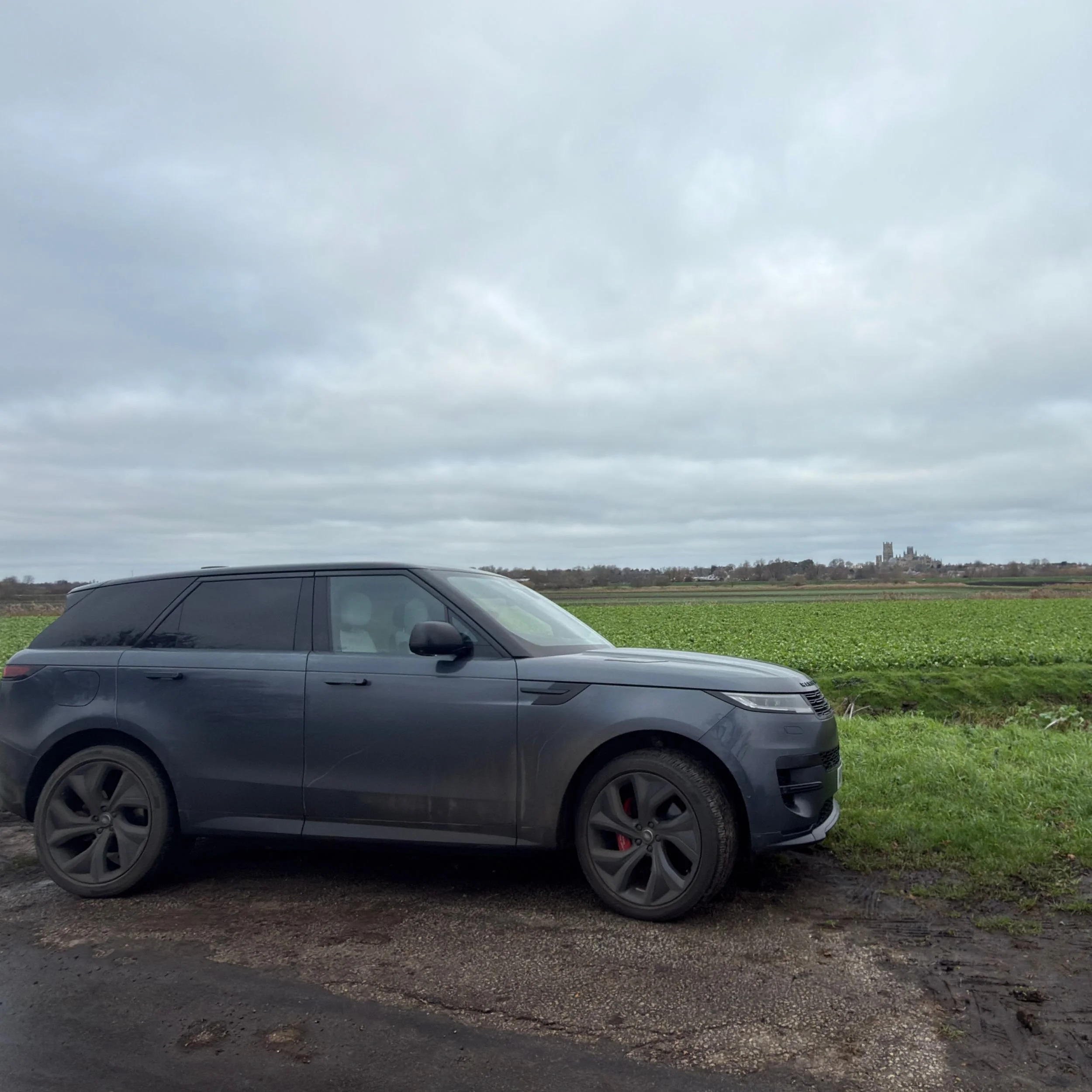 A Grey Range Rover Parked on Quanea Drove Ely with fields behind leading towards Ely Cathedral on the horizon