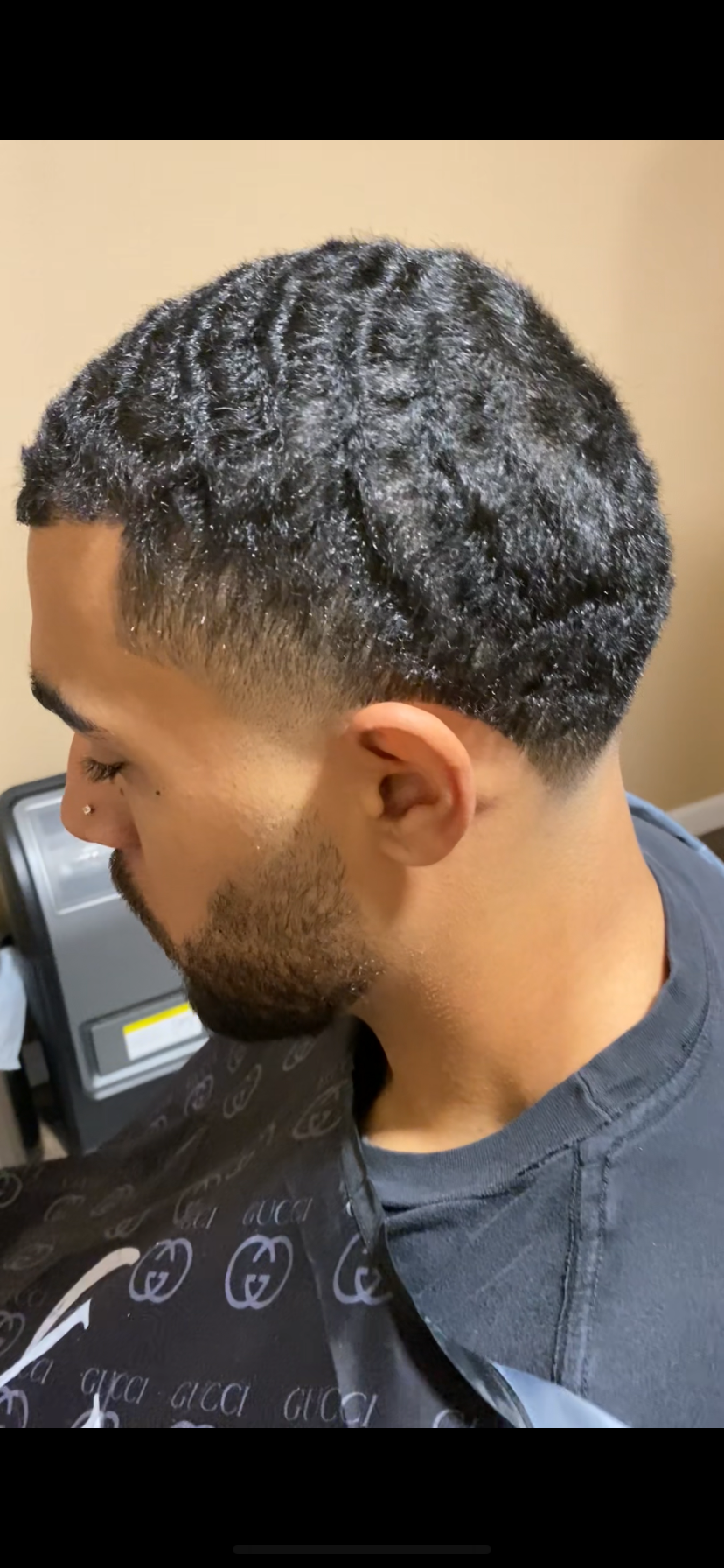 Side profile of a man with a fresh fade haircut featuring textured, wavy top hair and a closely shaved fade on the sides.