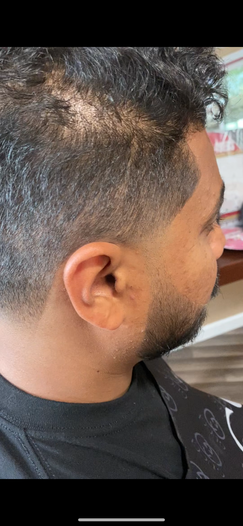 Side view of a man with a short fade haircut, including gray hair at the temples, and a beard.