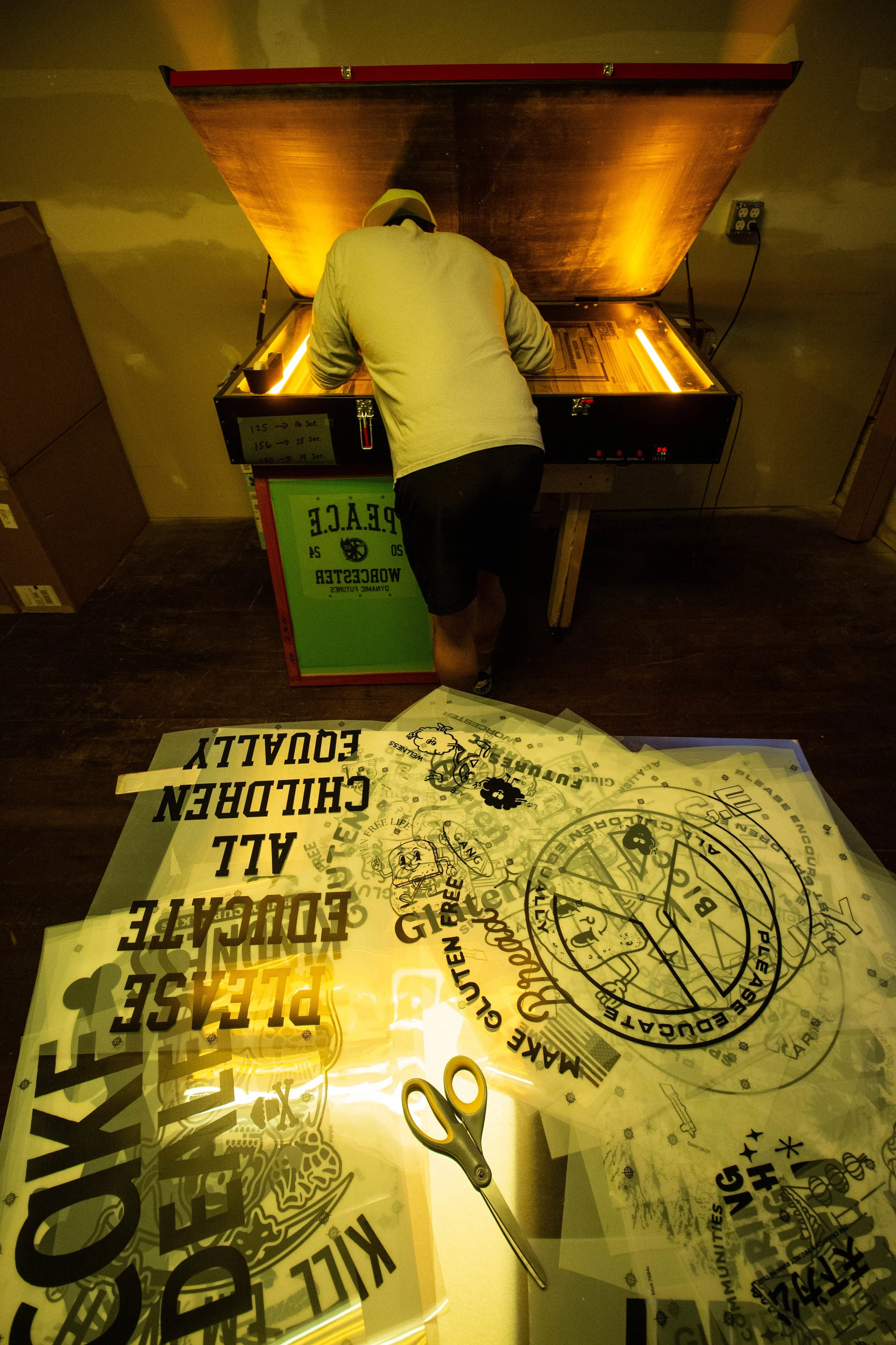 Person burning a screen printing screen in a darkroom.