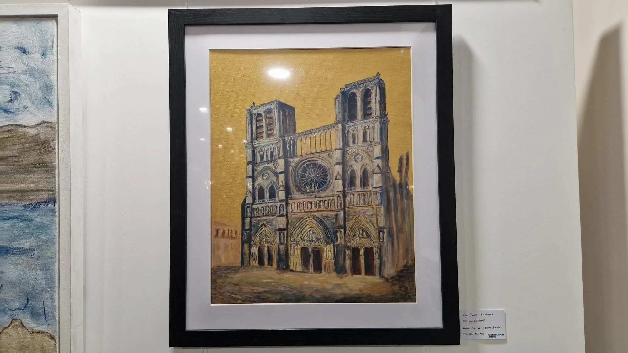 A framed oil painting of the Notre Dame in a local art exhibition.