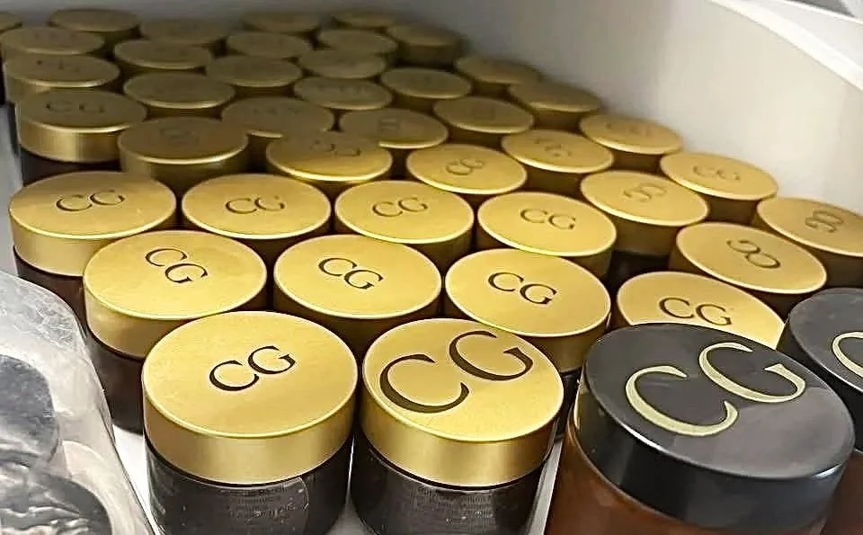 Multiple small containers with gold and black lids, labeled with the letters 'CG'.