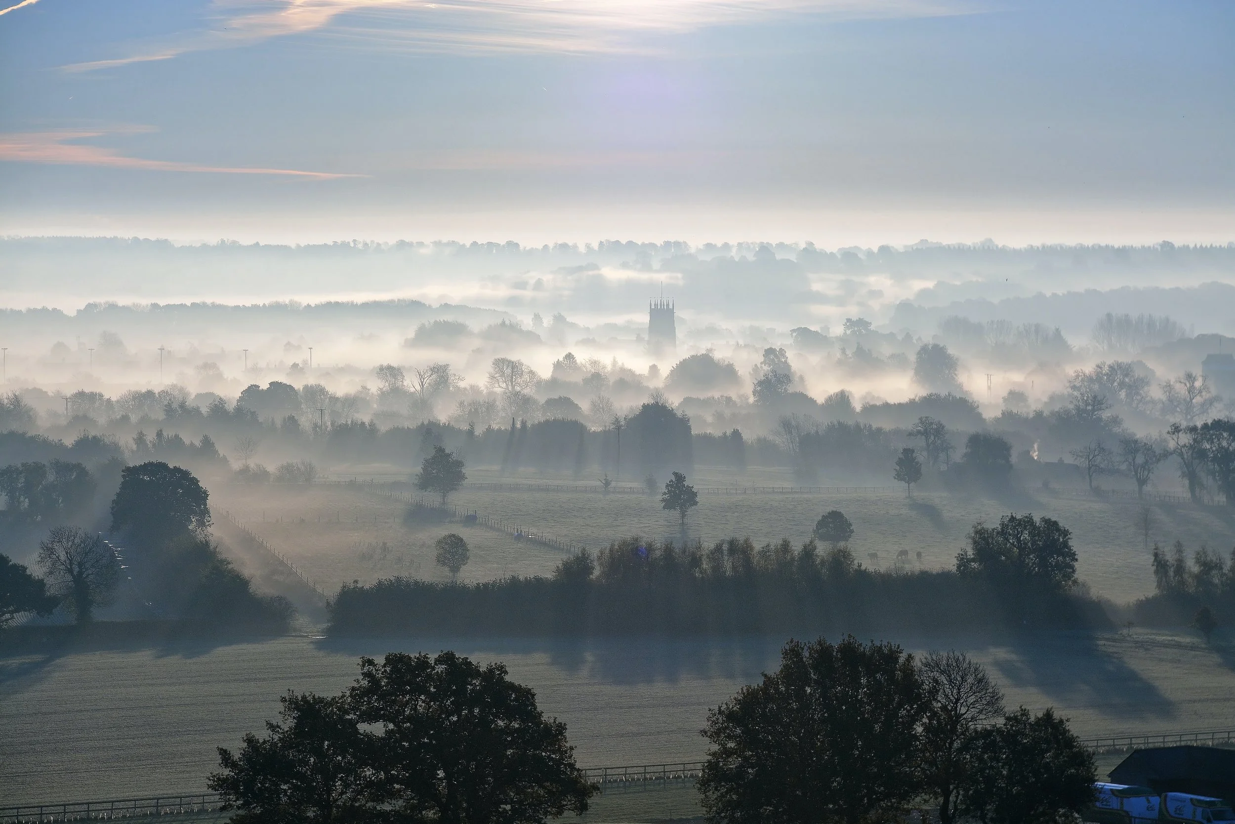 Landscape view of the Cotswolds, with a church in the centre distance