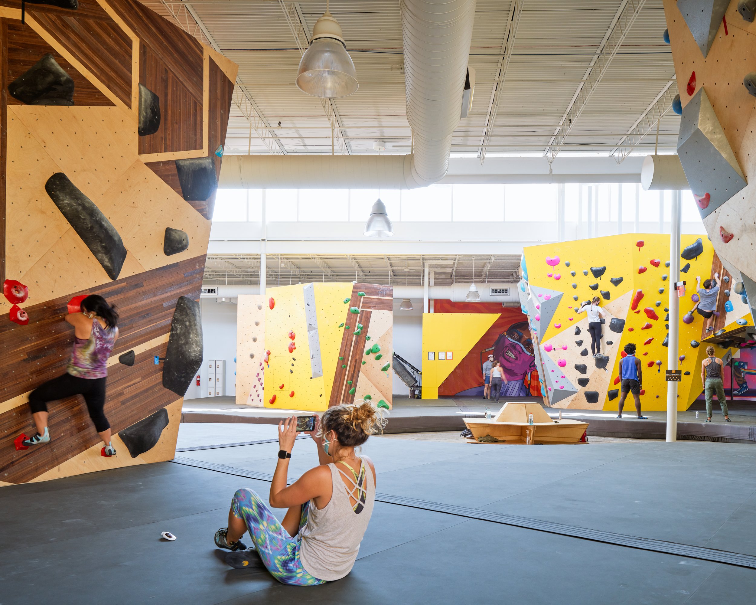 A wide view of Crux Central’s bouldering terrain reveals the spatial layering of walls, murals, and gathering zones—designed to support climbing, spectating, and community overlap.