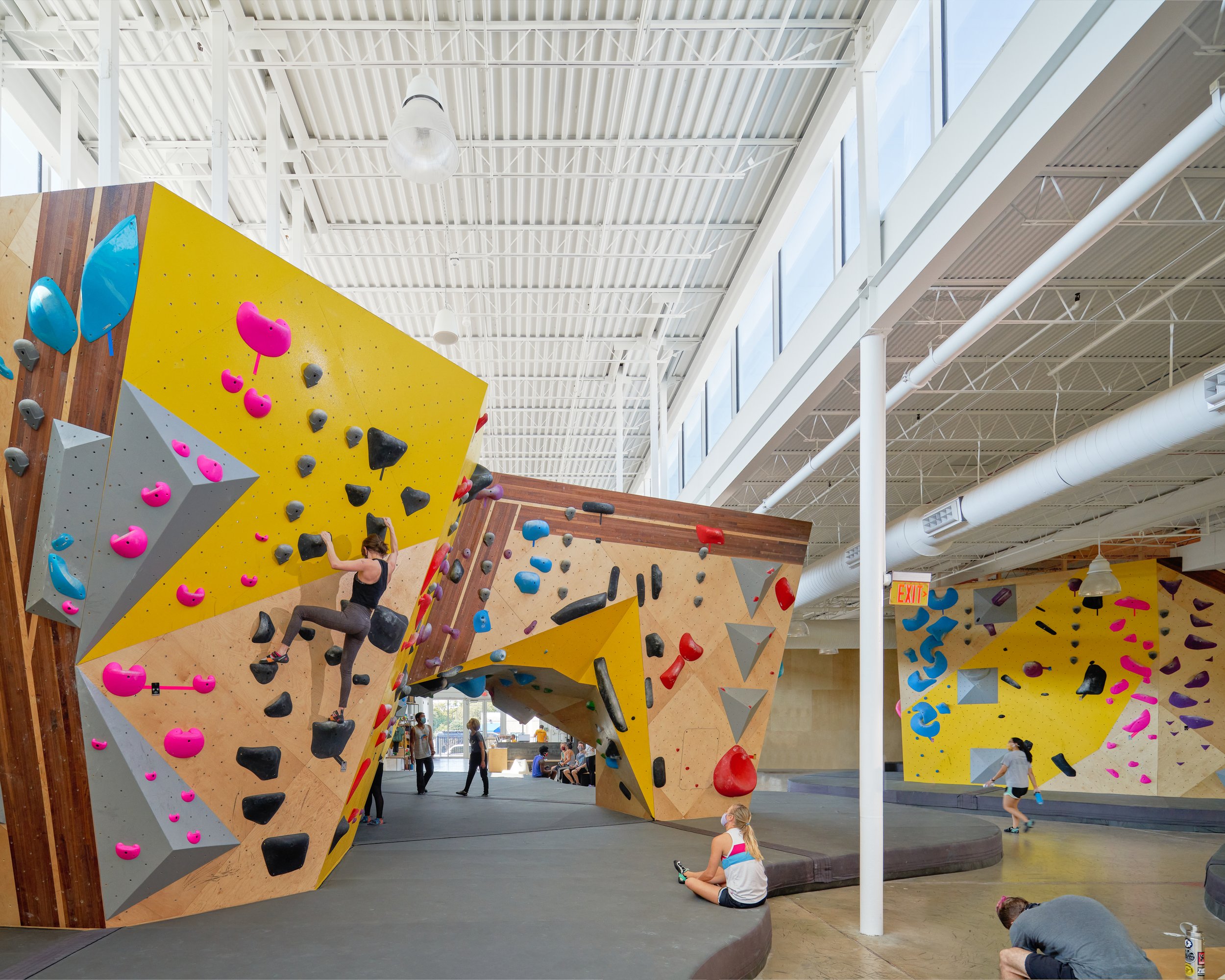This corridor-like moment shows how the gym’s bouldering volumes shape intuitive paths and framed views, while clerestory light enhances contrast and spatial rhythm.