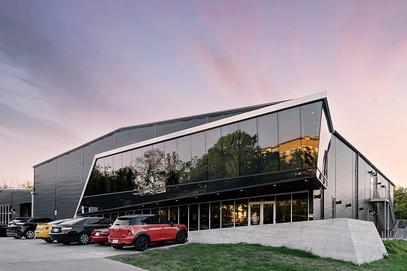 A sharp glass façade slices through the black metal exterior, signaling the building’s transformation from a warehouse to a vibrant climbing gym.