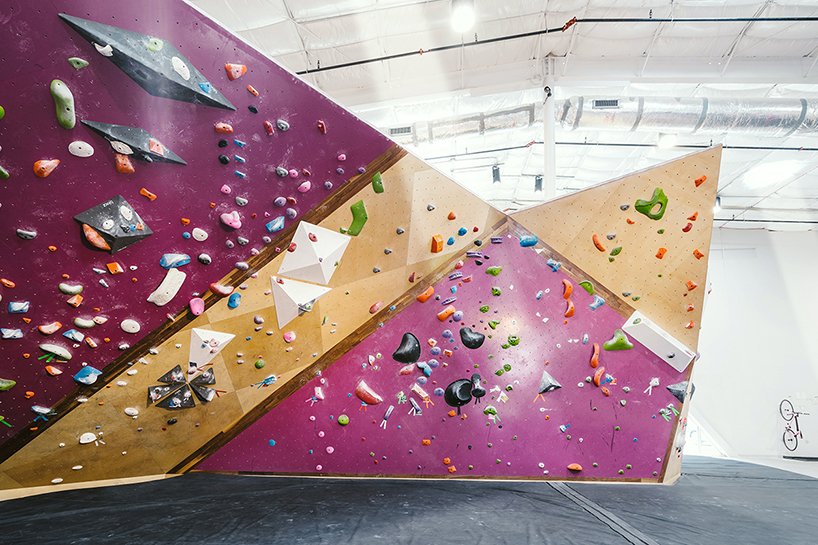 A bold palette and angled wall geometry energize this bouldering zone, where routes shift across faceted planes in vivid contrast.