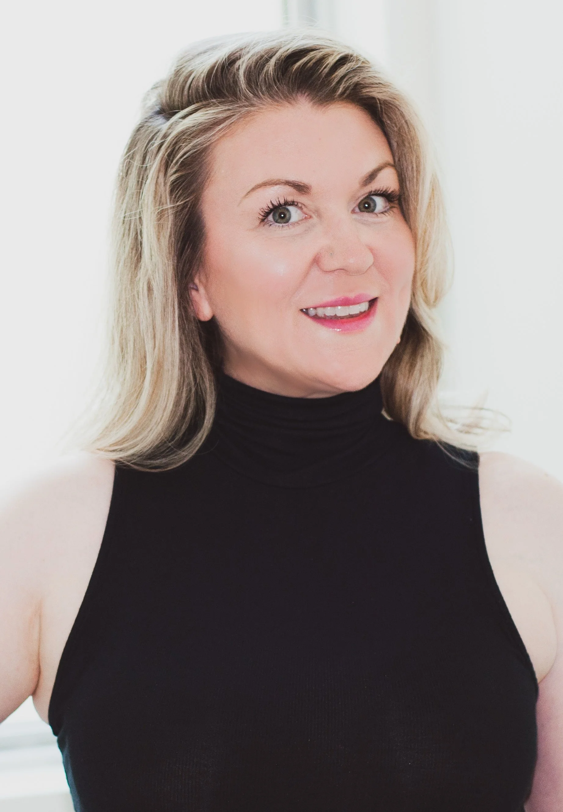 An Image of Sara shanks, a nurse at valere medical aesthetics, A woman with shoulder-length blonde hair, wearing a black turtleneck top, smiling at the camera.