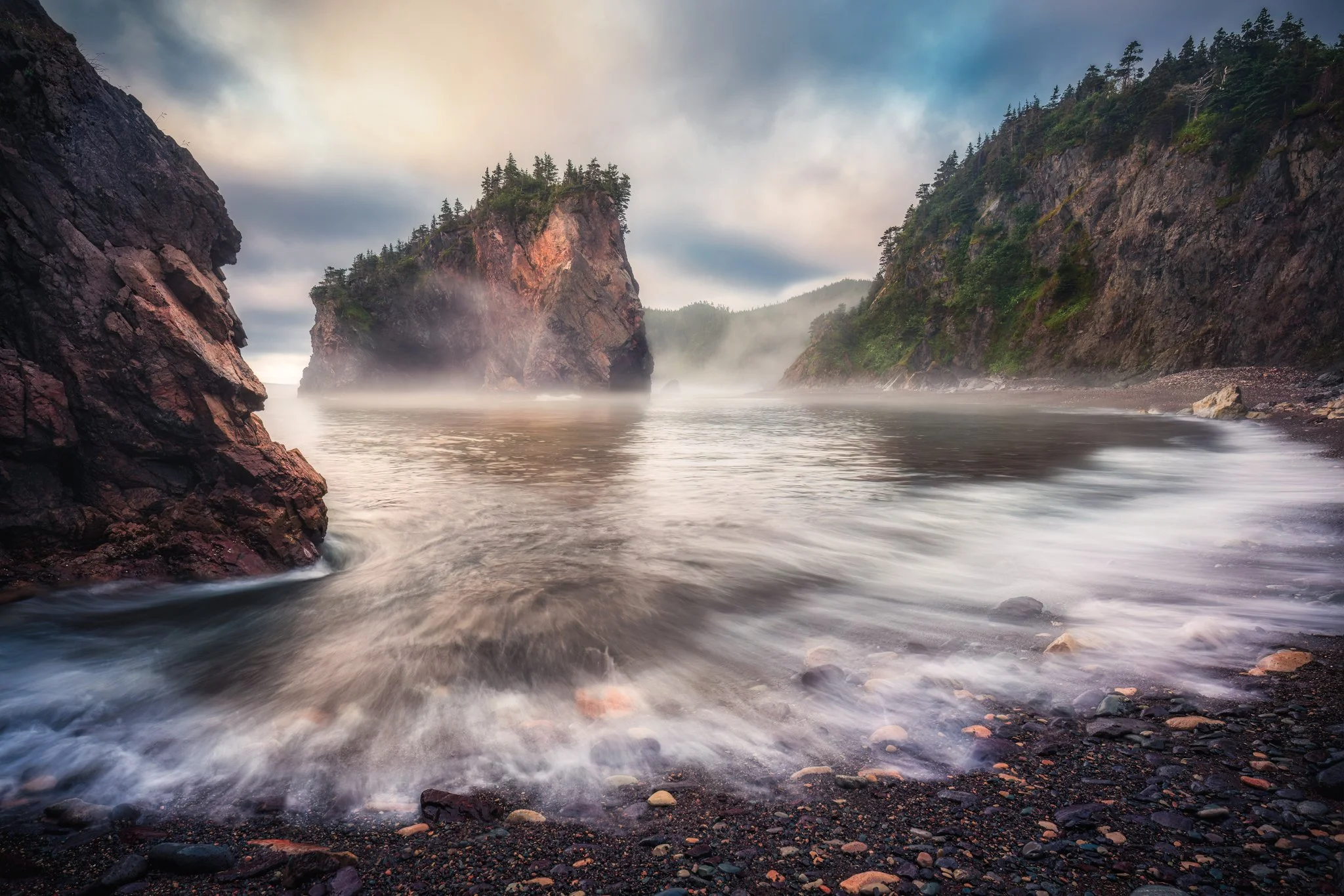 The waves roll along the beach as the mist lingers along the coast at Chance Cove Newfoundland.