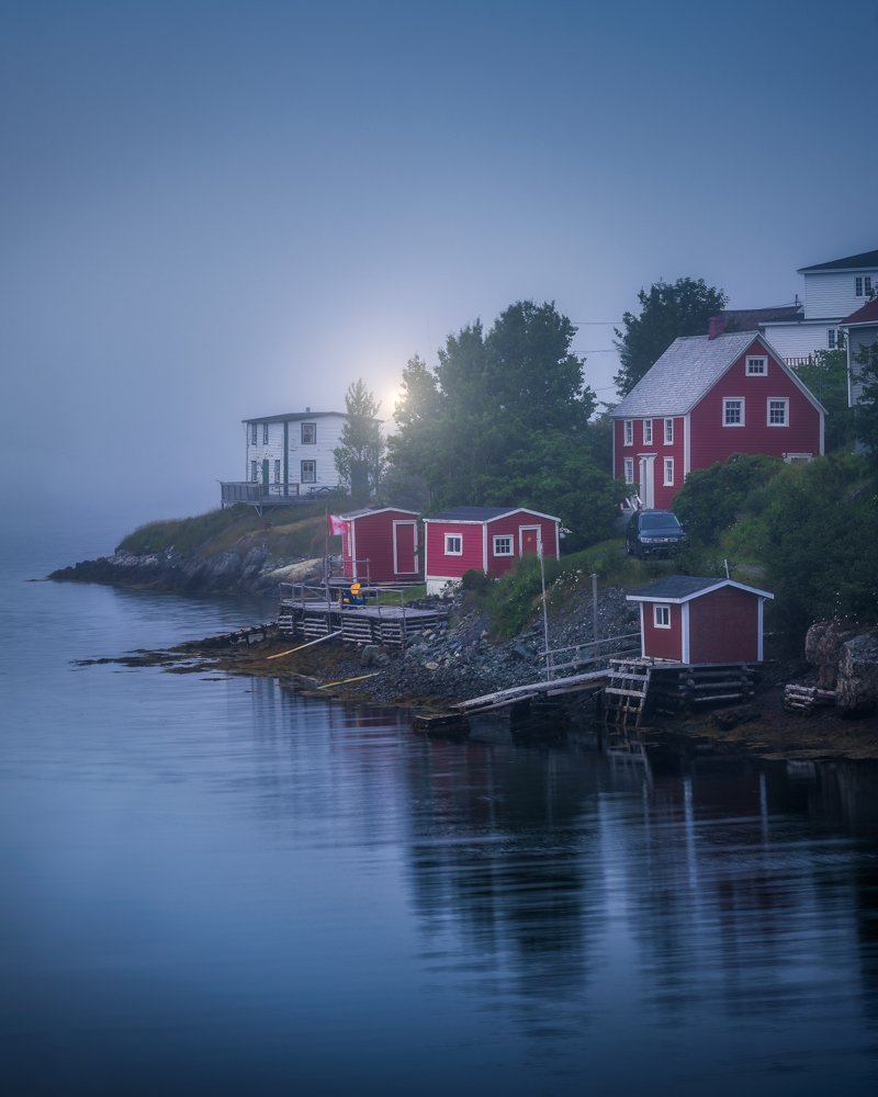A blue hour scene of the fog isolating old salt box houses at Burin Newfoundland.