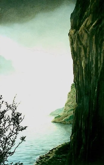 Cliffside view of a body of water with distant landforms and a foggy sky.