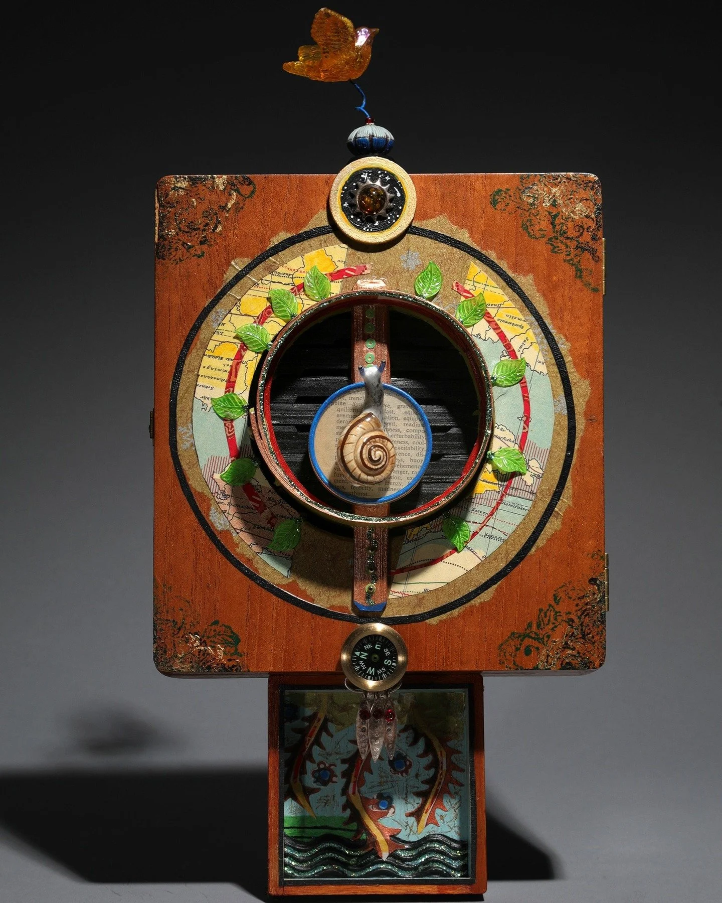 Crossing Over 
15&rdquo;h x 8&rdquo;w x 2&rdquo;d

This assemblage tells the story of a profound journey of transition. The snail at the center of this piece is poised between two different navigation systems. Below, the compass has been a steady sou