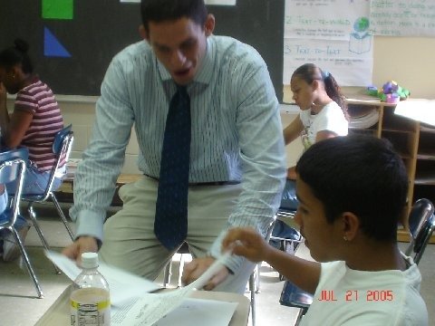 Eli Savit helping a student in a classroom setting.