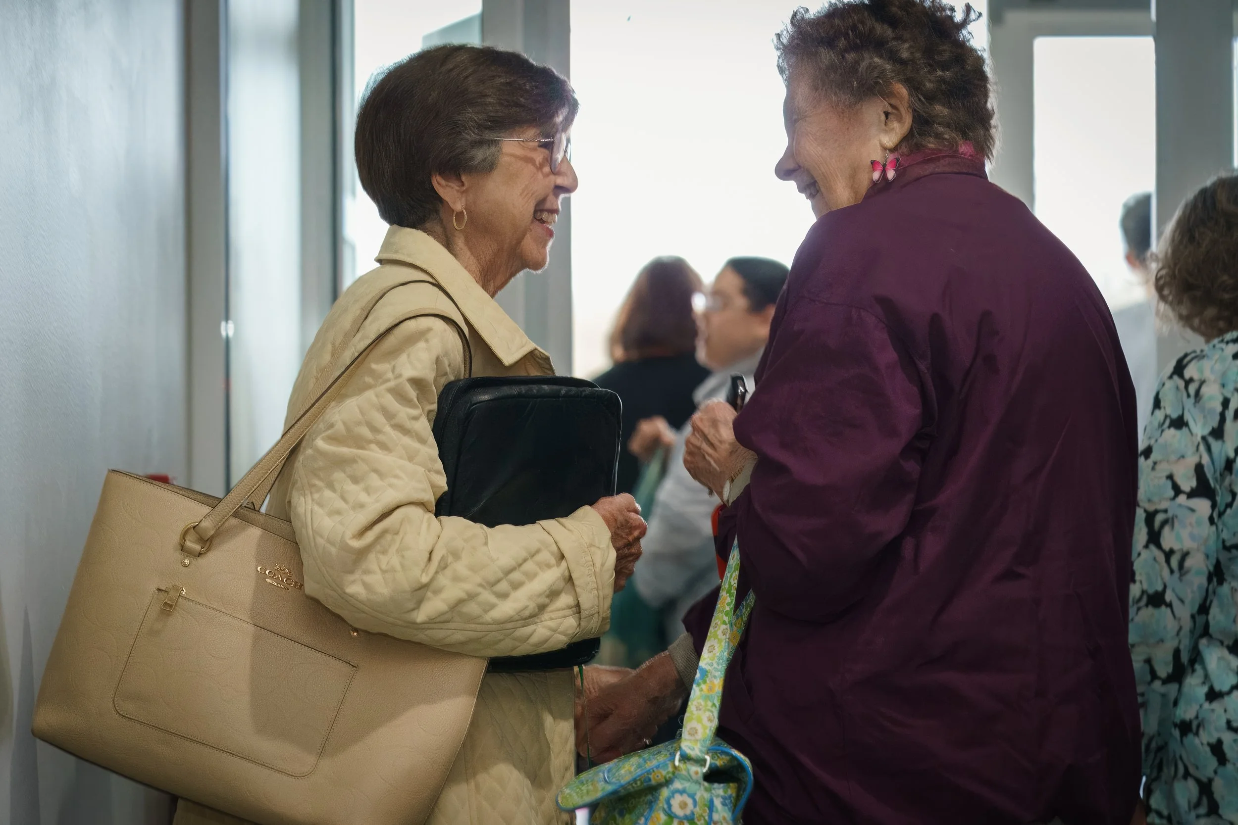 Two women smiling and holding hands as they greet each other after church service at Victory Life Church located in Stow, OH, near Fairlawn, OH,