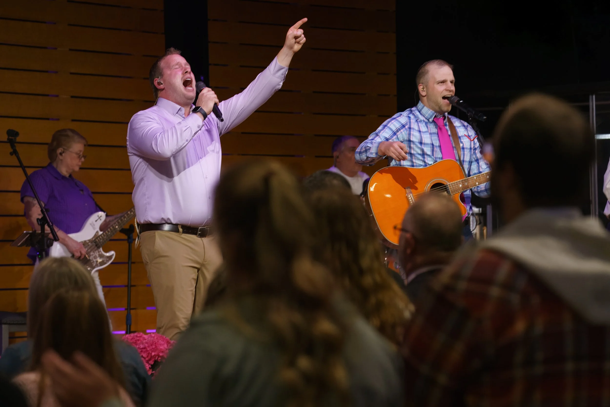 Two men singing on stage, one with a microphone and the other playing an acoustic guitar, with congregation visible. Victory Life Church in Stow, OH, near Hudson, OH.