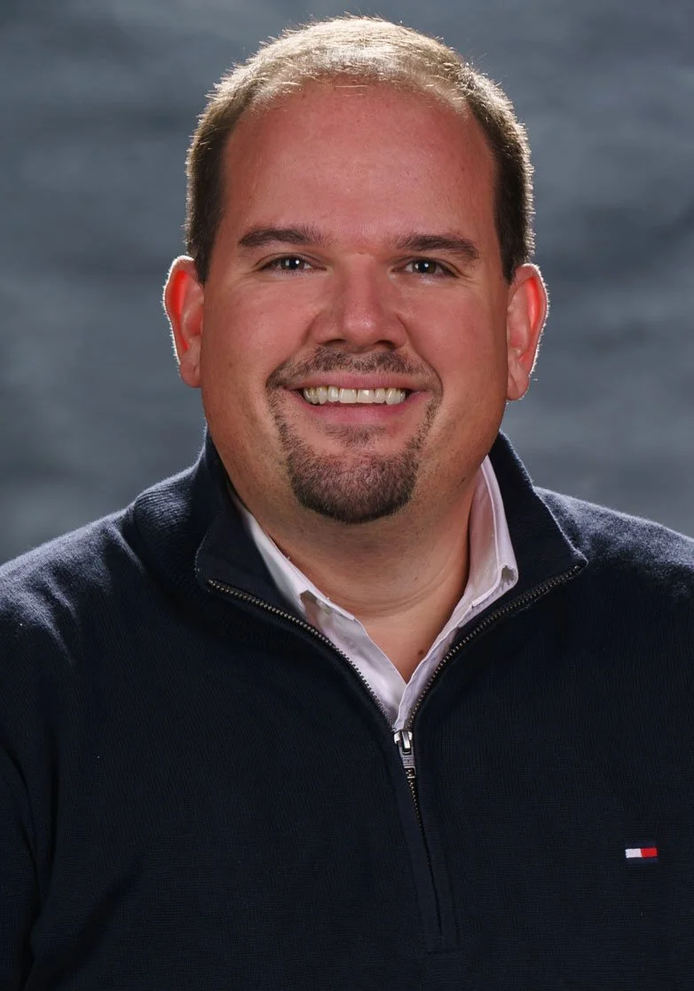 Pastor Matt Skifstad, Pastor of Victory Life Church in Stow, OH. Smiling man with short brown hair and a goatee, wearing a navy blue zip-up sweater over a white collared shirt, with a blurred outdoor background.