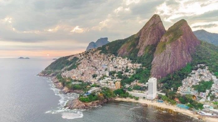 Aerial view of a coastal city nestled between mountains and the ocean at sunset.