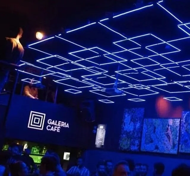 Interior of Galeria Cafe with futuristic LED ceiling lights and a large digital screen on the wall, filled with people enjoying the space.