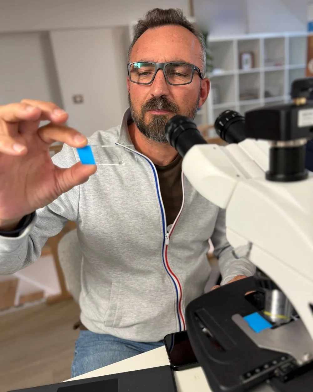 Sébastien Vieuxbled tient une lame de prélèvement devant un microscope