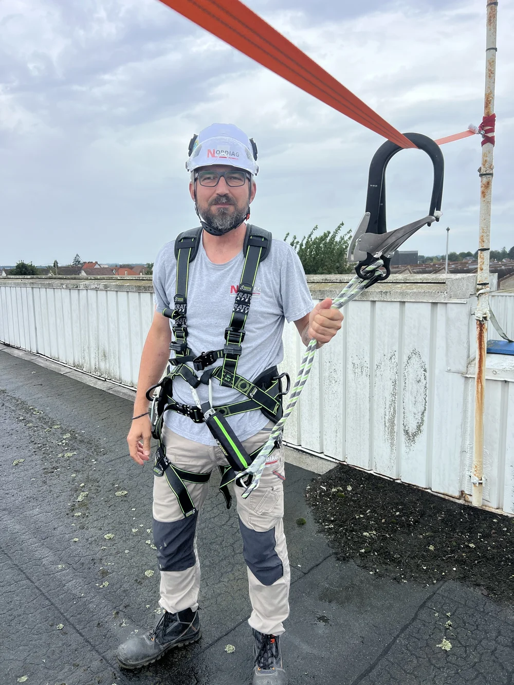 Sébastien Vieuxbled équipé d'un harnais antichute, relié à une ligne de vie sur une toiture-terrasse