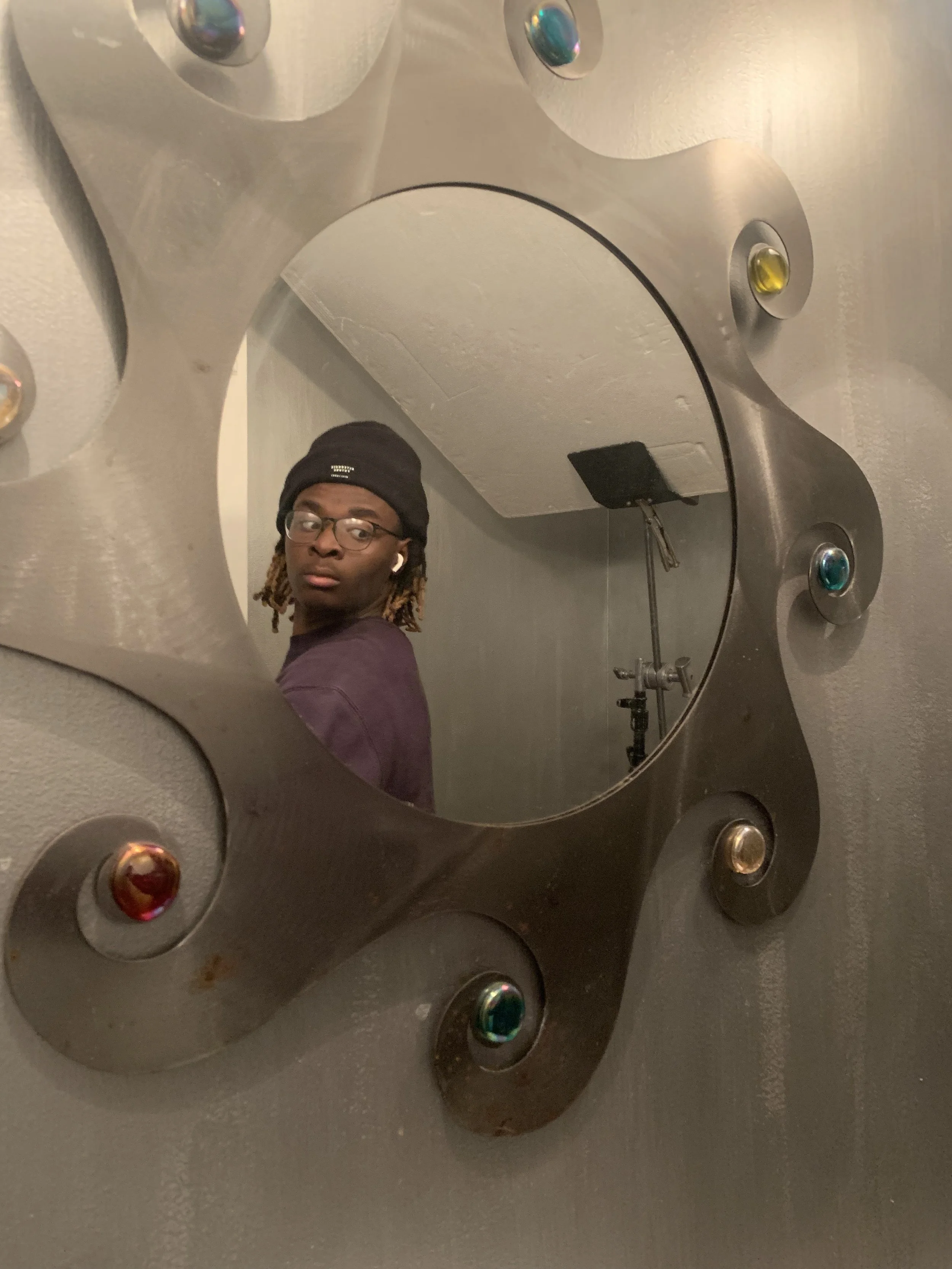 Person taking a photo in a decorative mirror adorned with colorful stones.