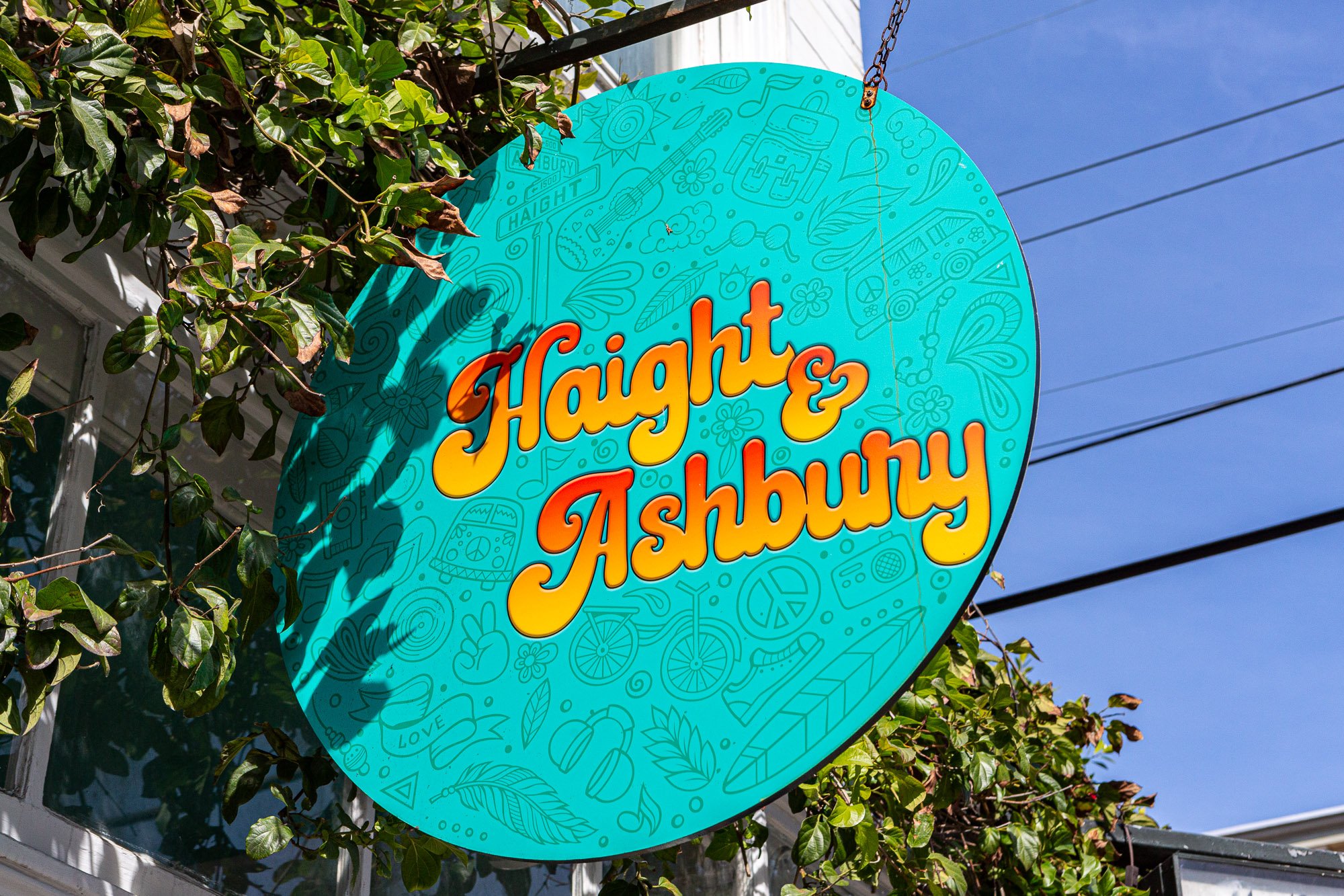 Colorful sign with 'Haight & Ashbury' and doodles, green leaves and blue sky