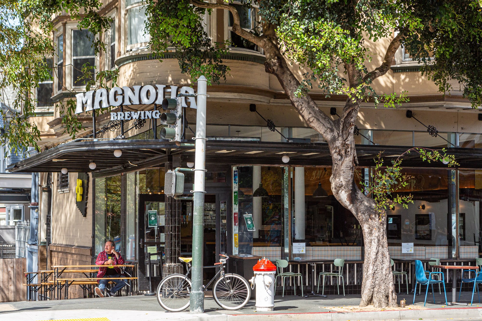 Exterior of Magnolia Brewing with outdoor seating and a bicycle parked nearby.