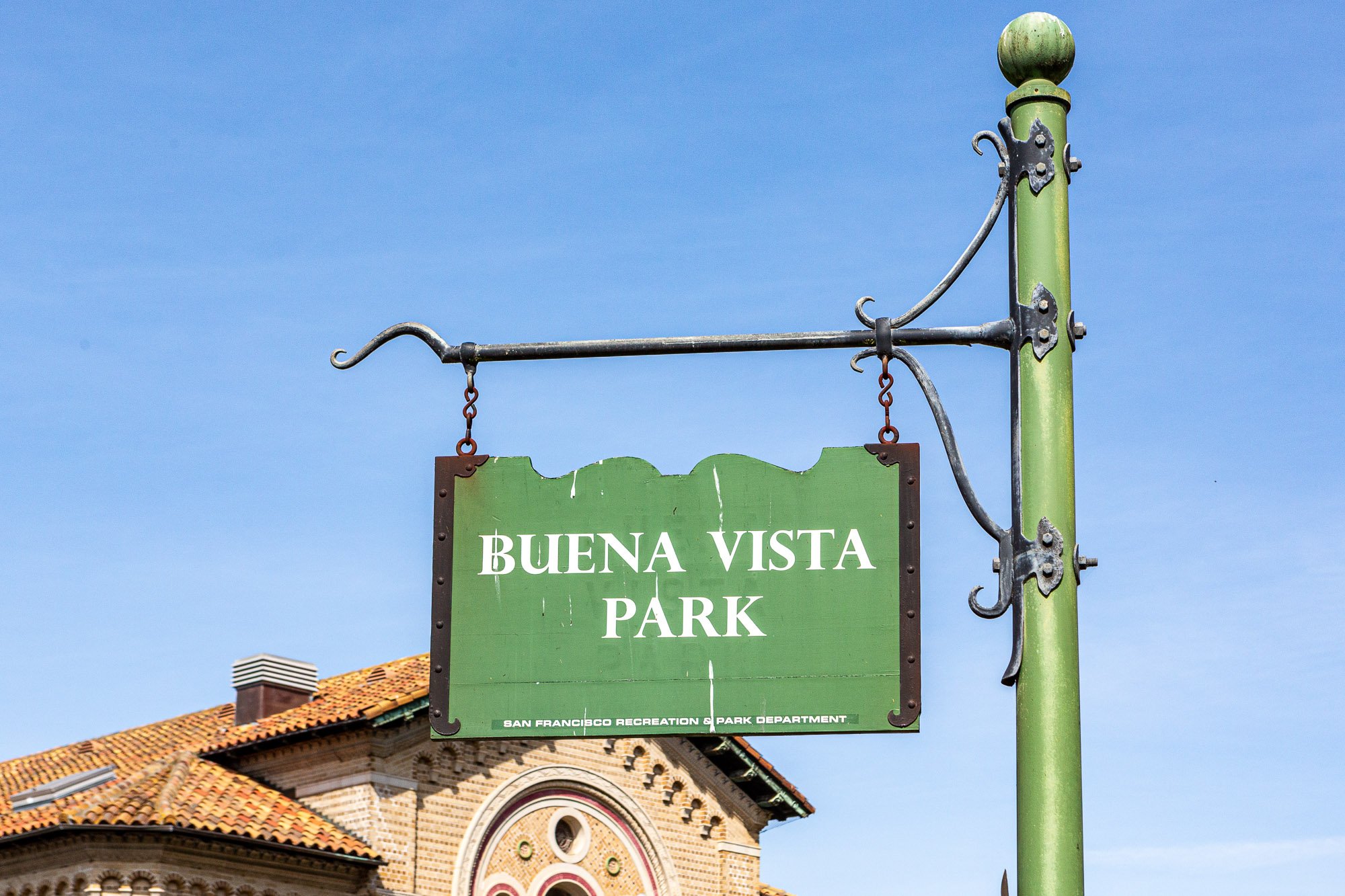 Sign for Buena Vista Park, San Francisco, against a blue sky background with part of a building visible.