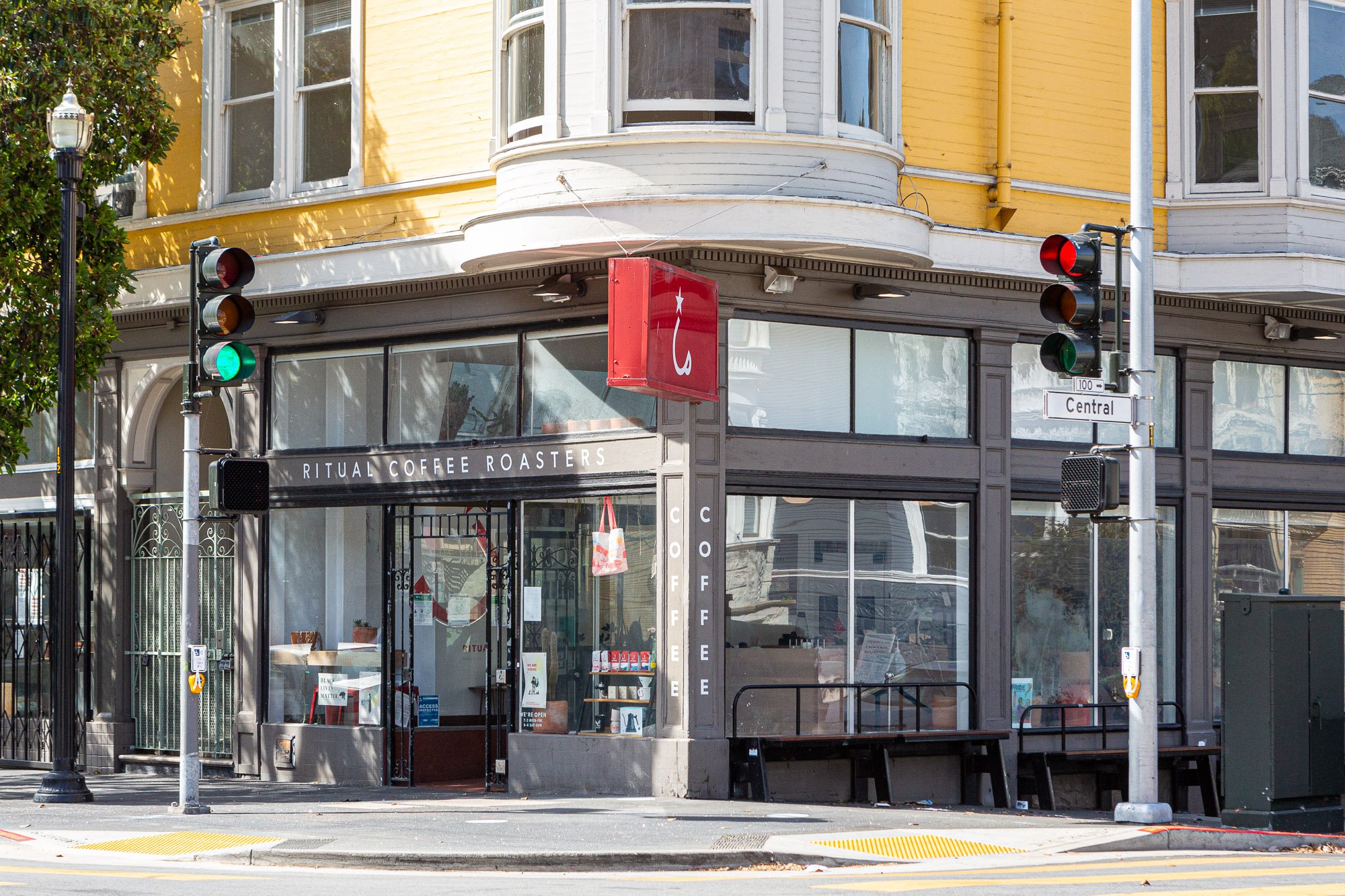 Street corner with a Ritual Coffee Roasters shop in a yellow building, traffic lights, and a pedestrian crosswalk.