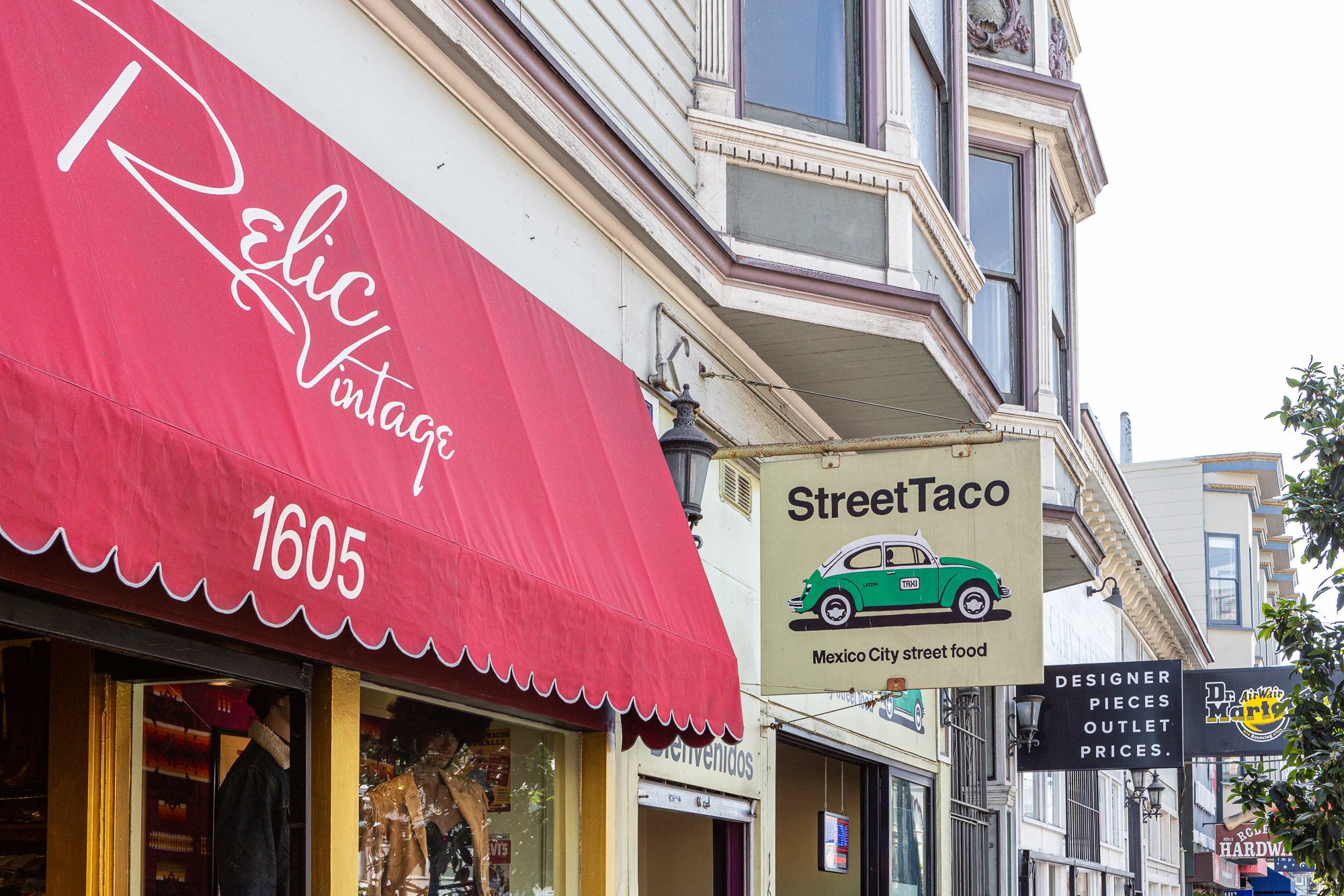 Storefront signs including "Relic Vintage" with a red awning, "StreetTaco" featuring a green car illustration, and a sign for designer outlet prices.